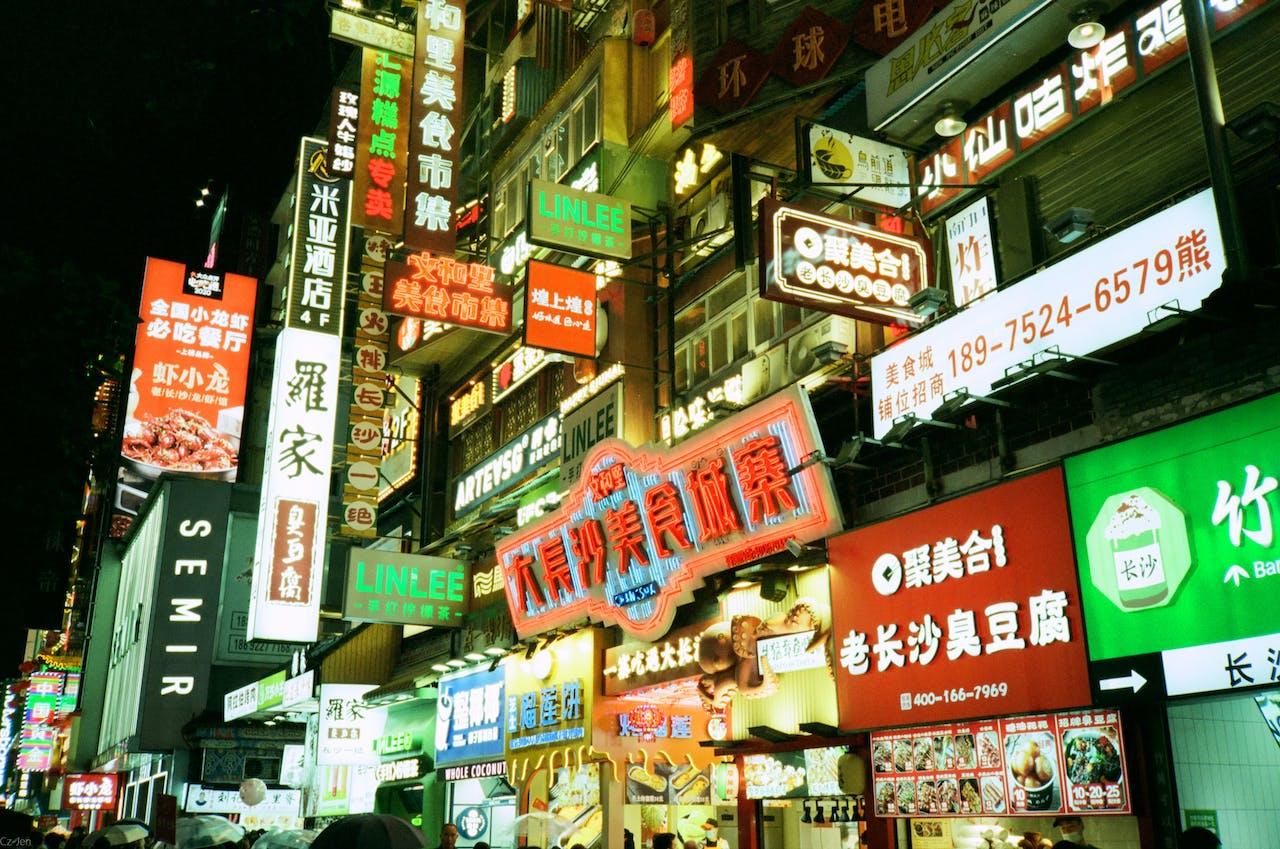 A busy part of a city with dozens of lit-up signs in Chinese