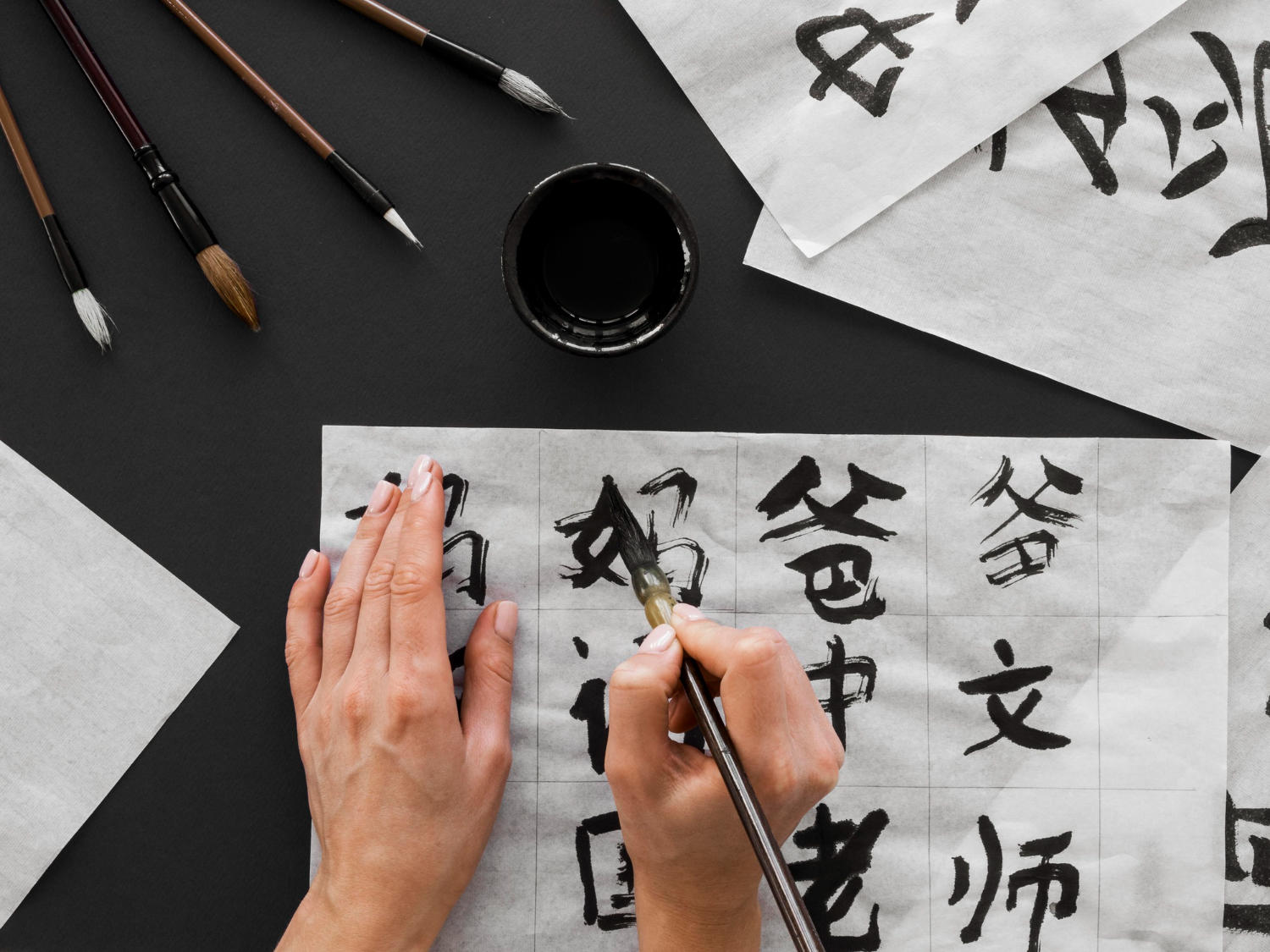 Top view of a person writing Chinese calligraphy with a brush