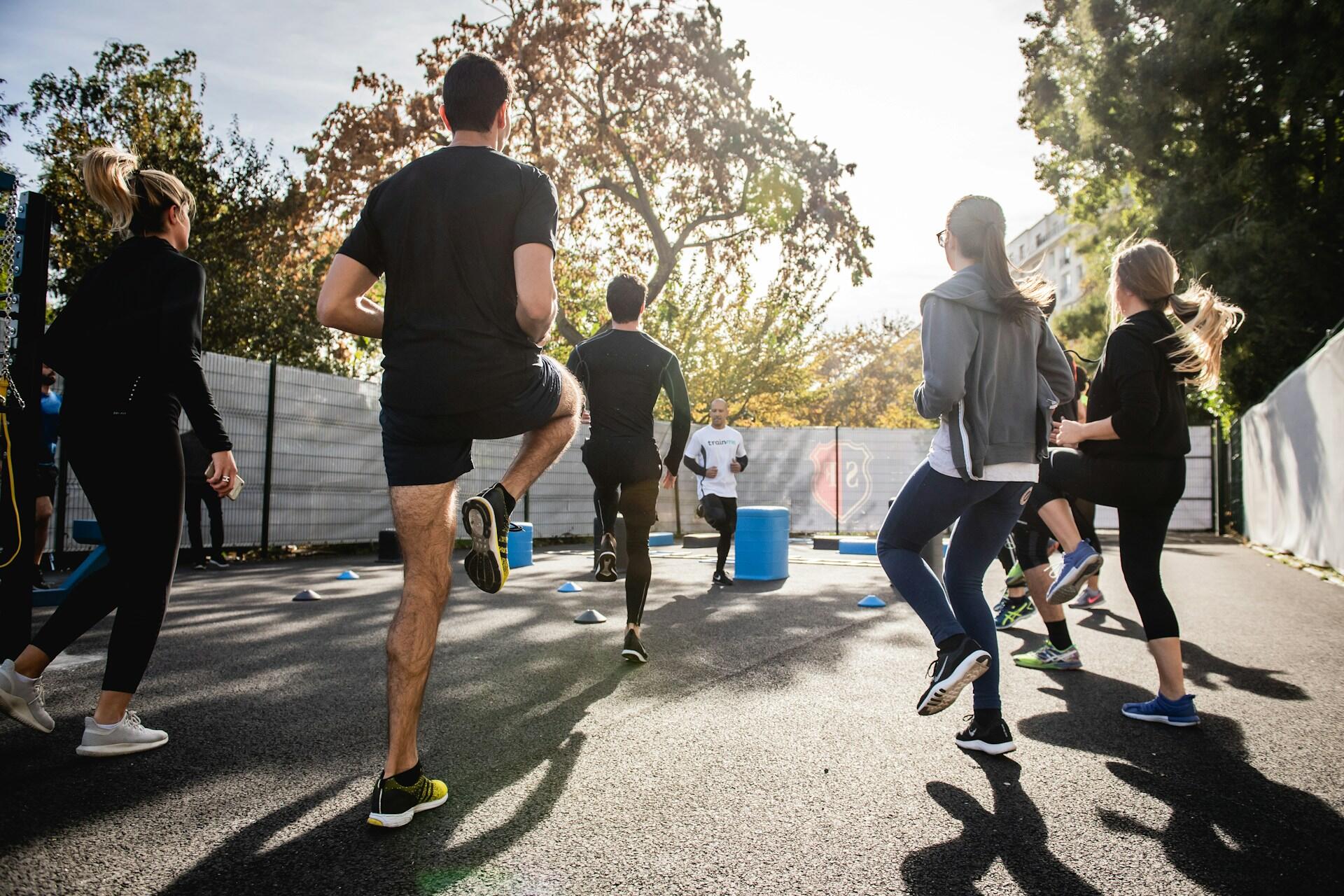 Group of adults doing high-knee exercises during an outdoor fitness class
