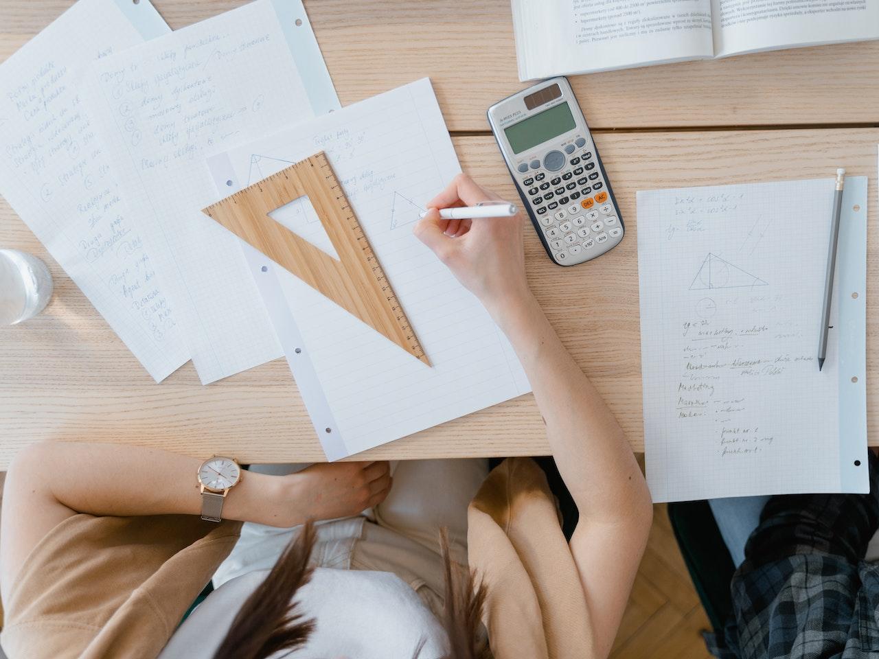 A student uses a calculator and other tools for their maths problems.