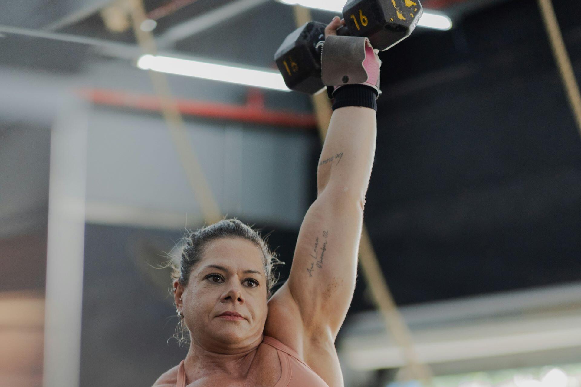 Woman performing an overhead dumbbell exercise during an upper body workout