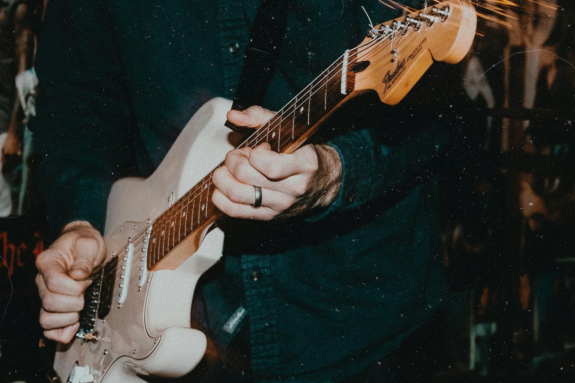 A person playing a Fender Stratocaster.