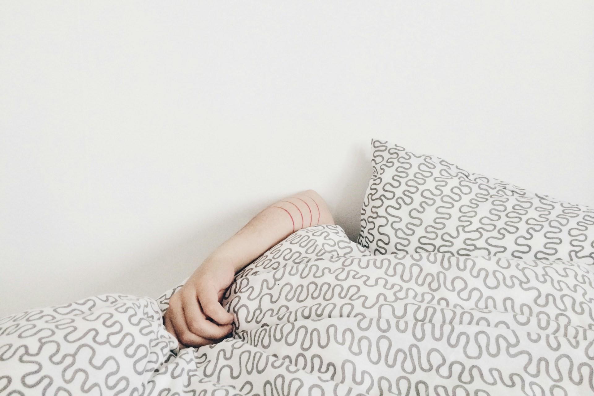 A person under a blanket in bed.