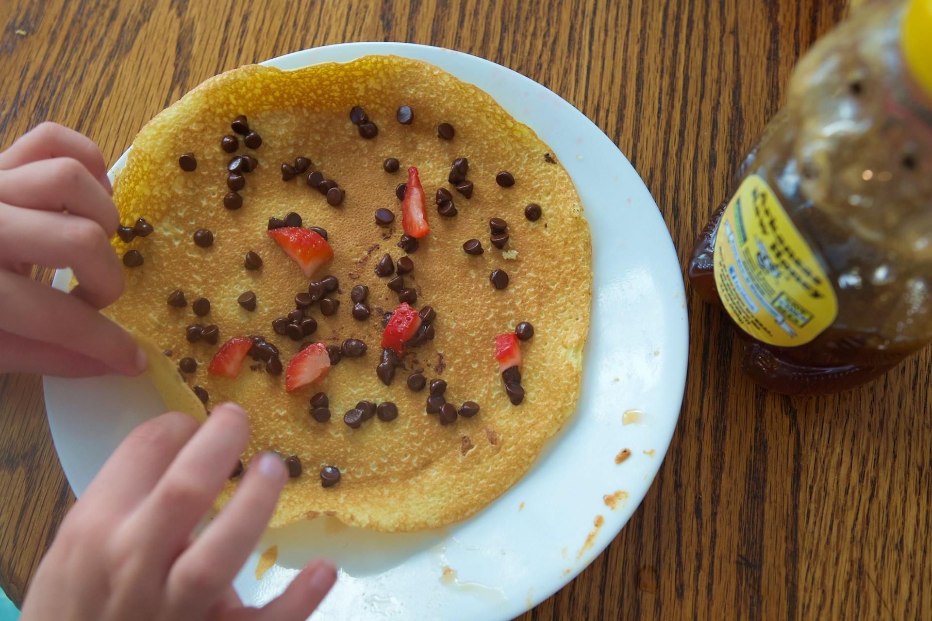 A crepe with chocolate chips and strawberries.