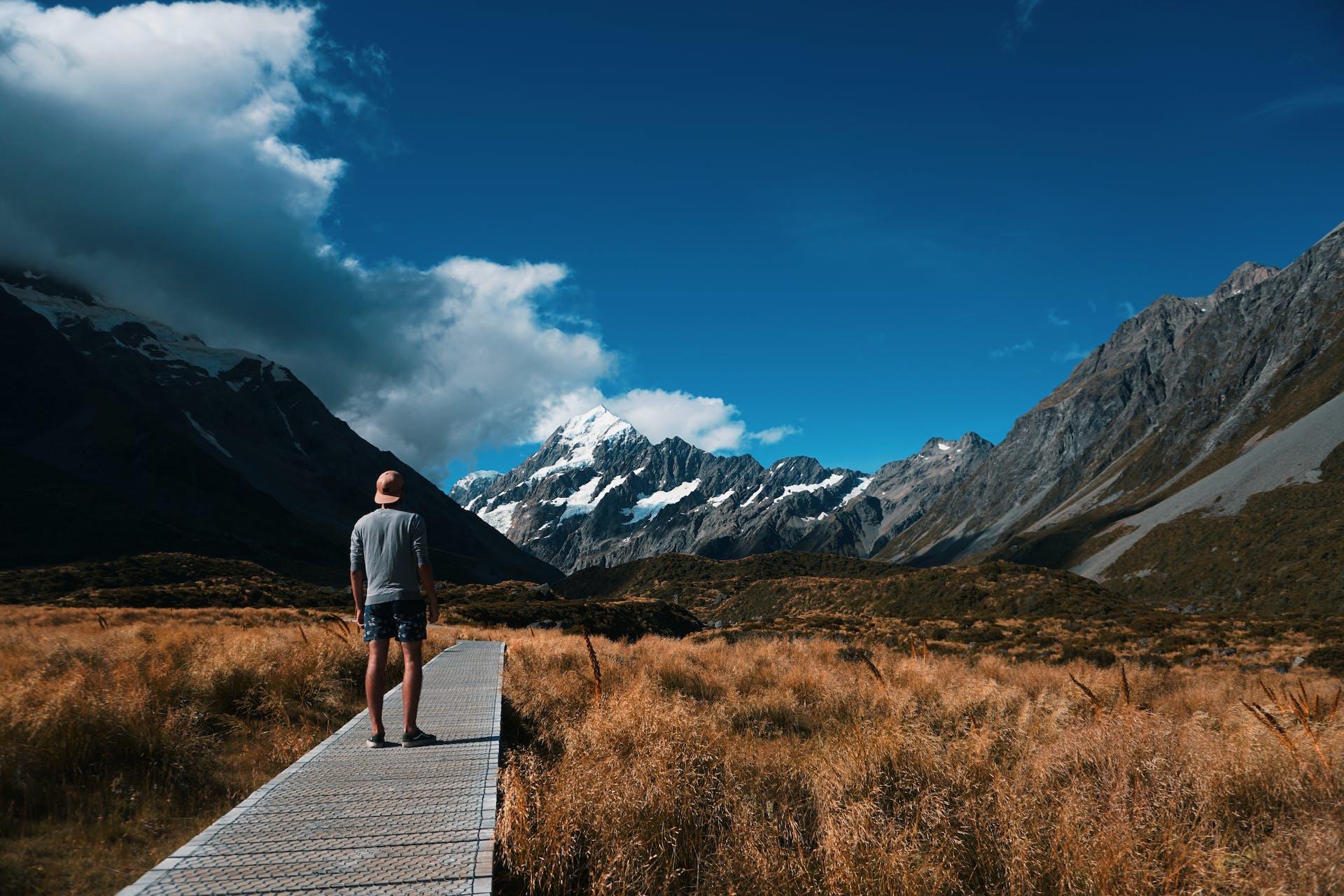 A person standing in the foreground with Mount Cook in the background