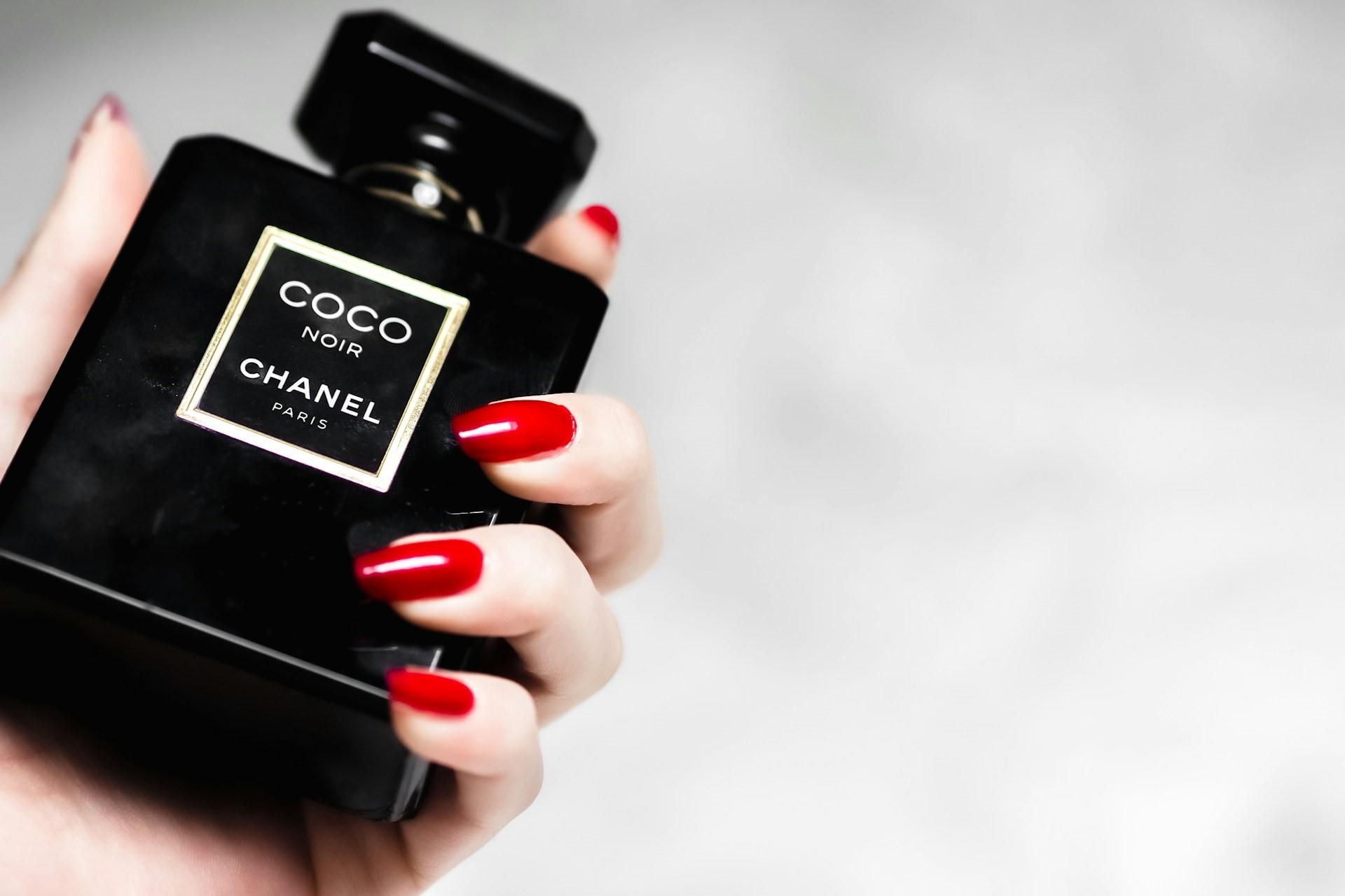 A hand holding a Coco Chanel perfume bottle.
