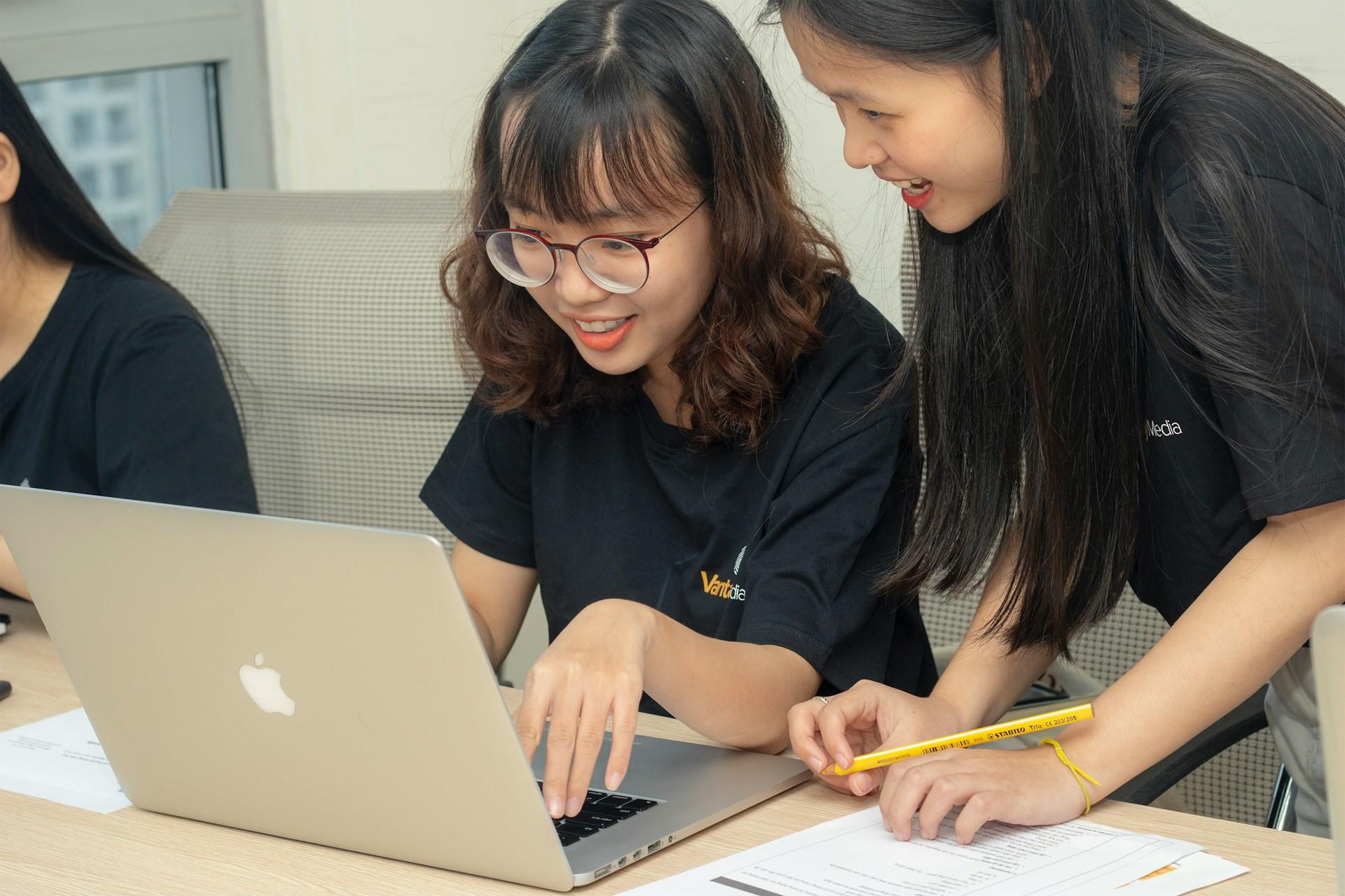Two students working on an Apple laptop.
