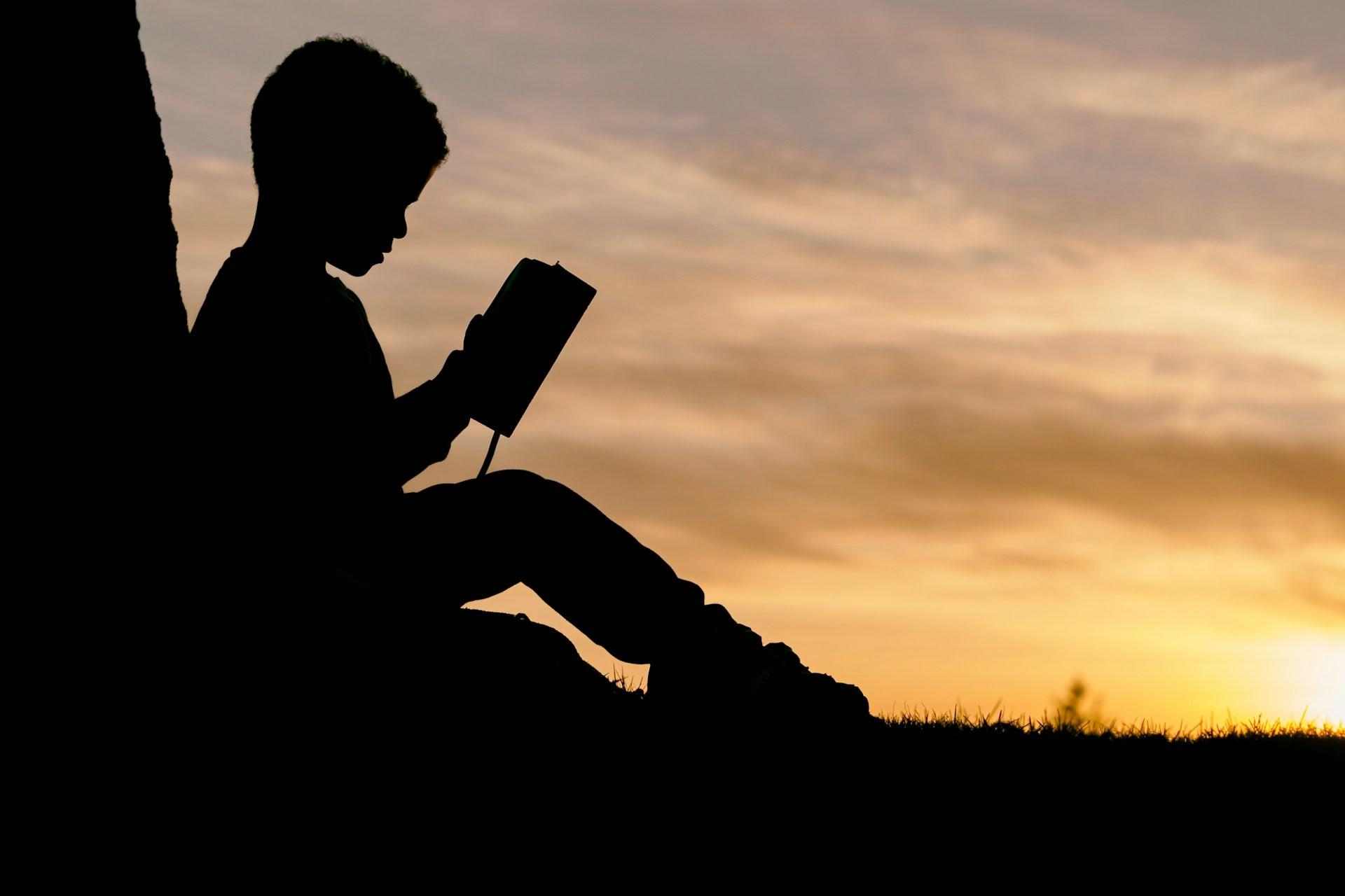 A child reading outside at sunset.