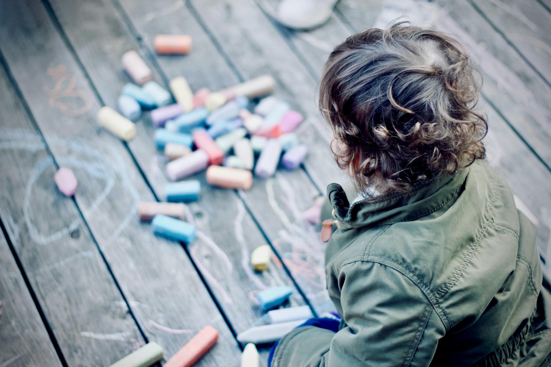A child drawing on a deck with chalk.