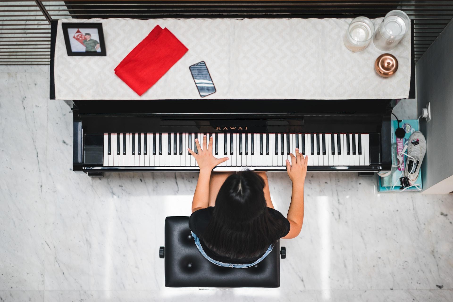 Overhead view of a person playing a white piano.