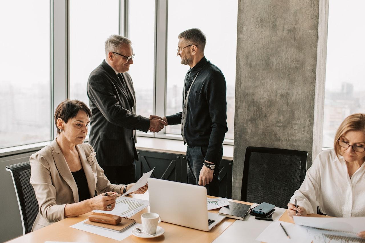 Two businessmen shake hands in a business office.