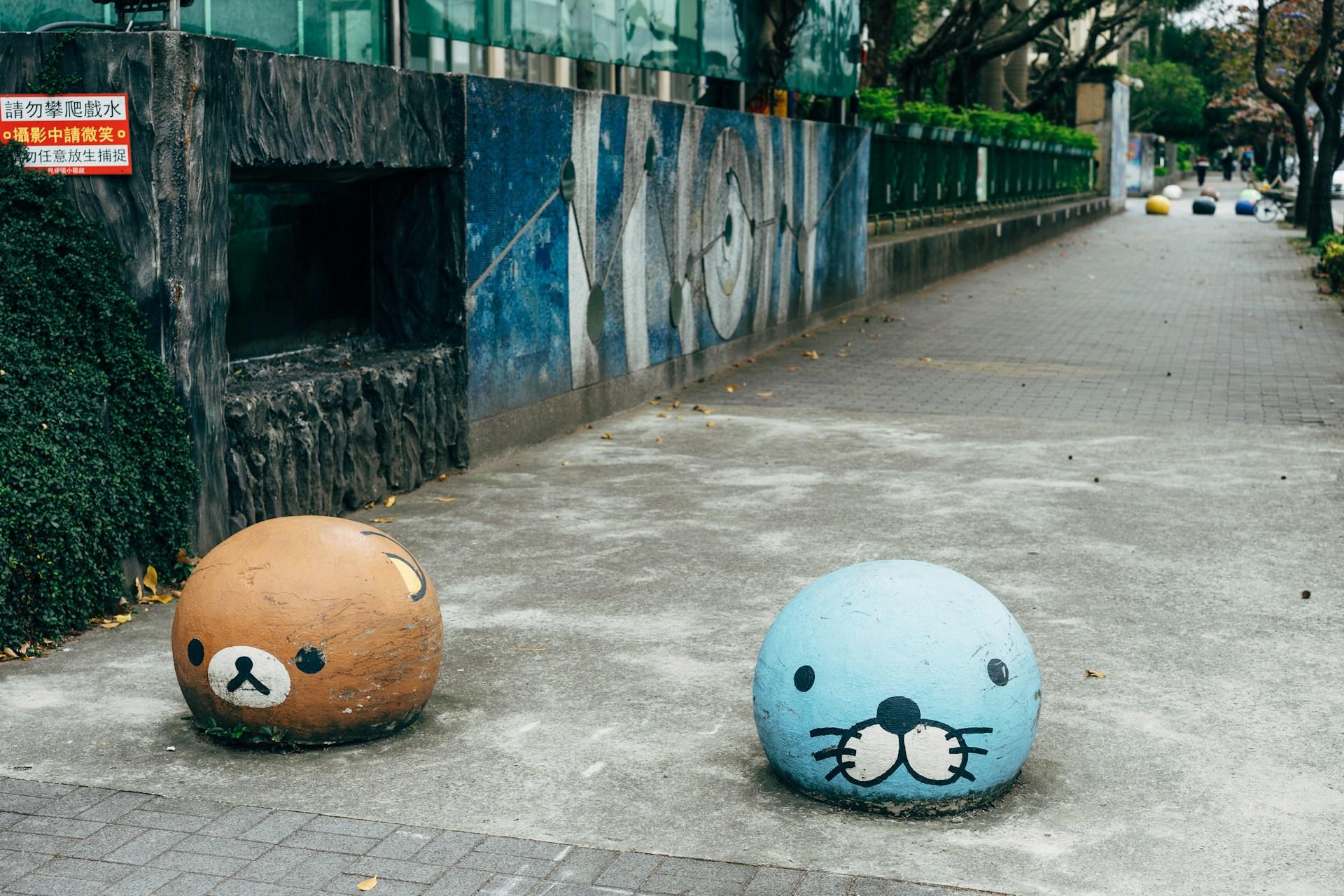 Kawaii art painted onto two bollards in a street.