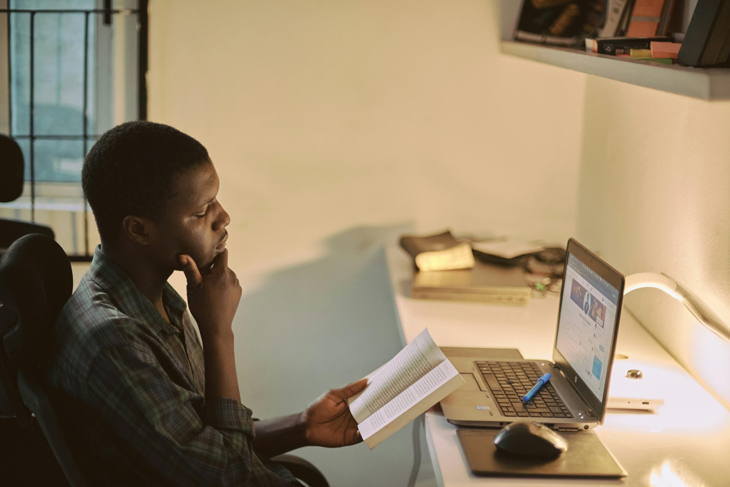 Man with book and computer studying