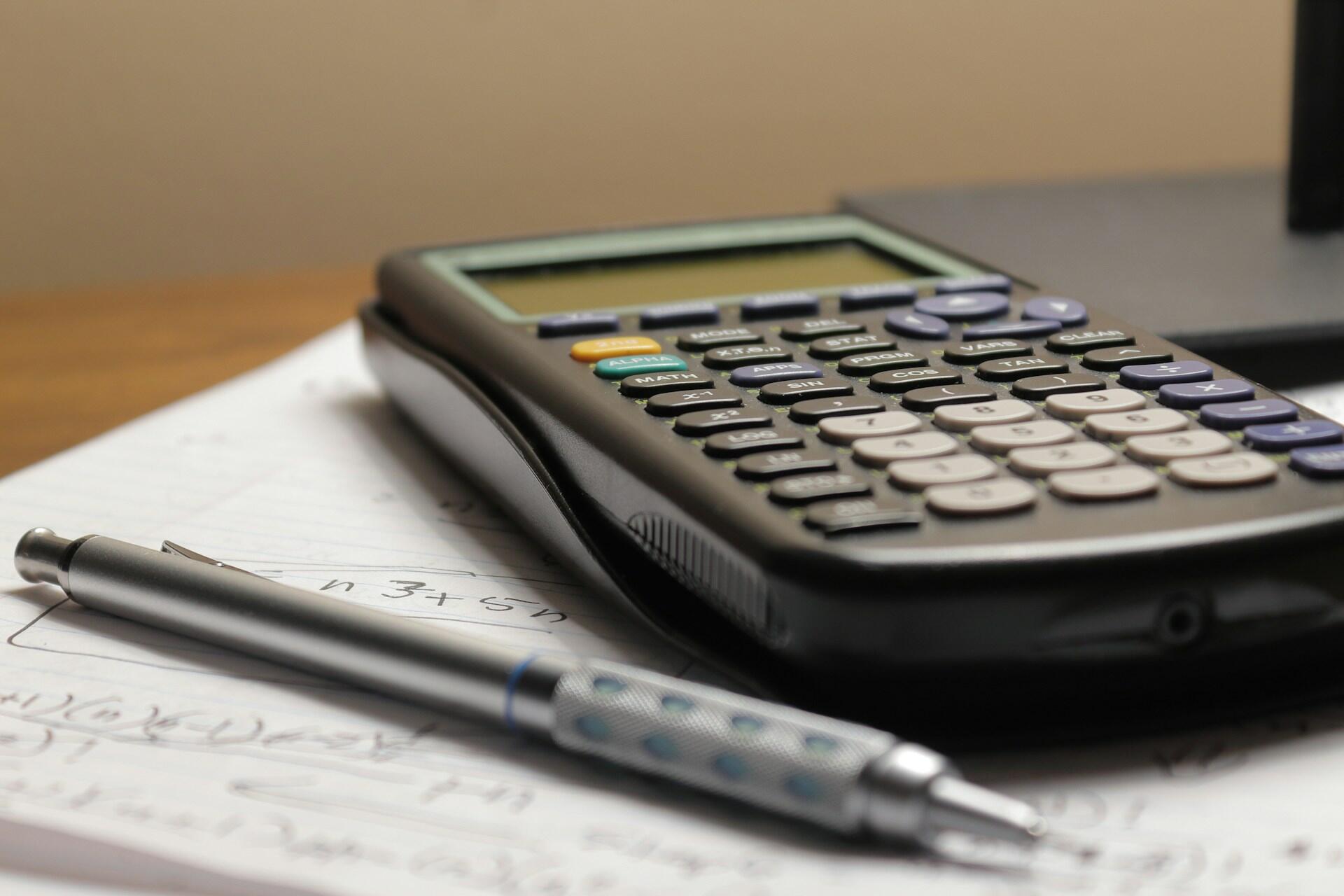 Scientific calculator and pen on a notebook with handwritten maths working