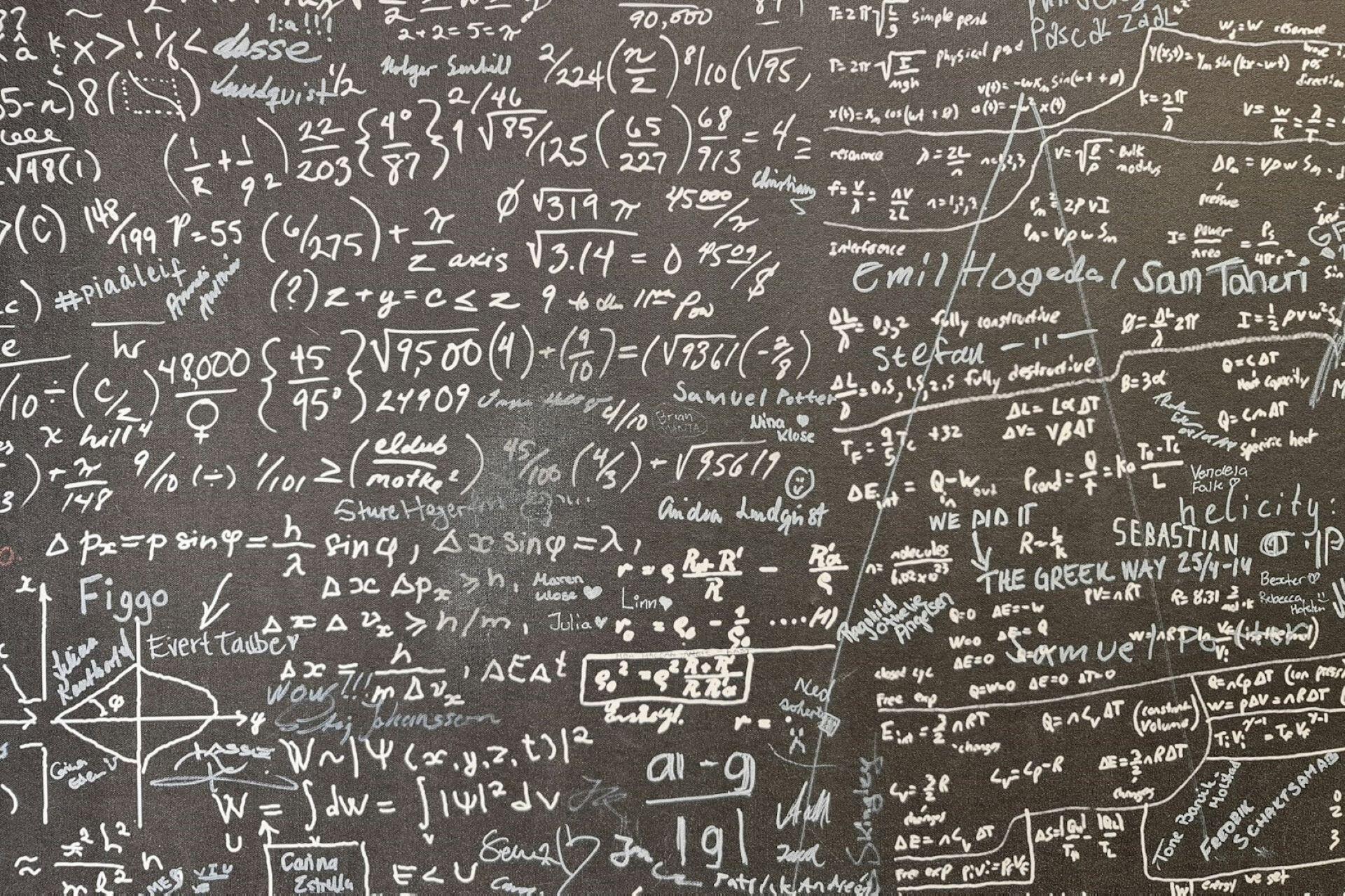 Chalkboard covered with maths formulas, equations, graphs and handwritten notes