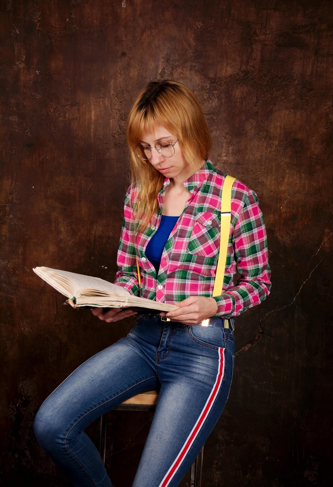 red haired women in suspenders reading hardback book
