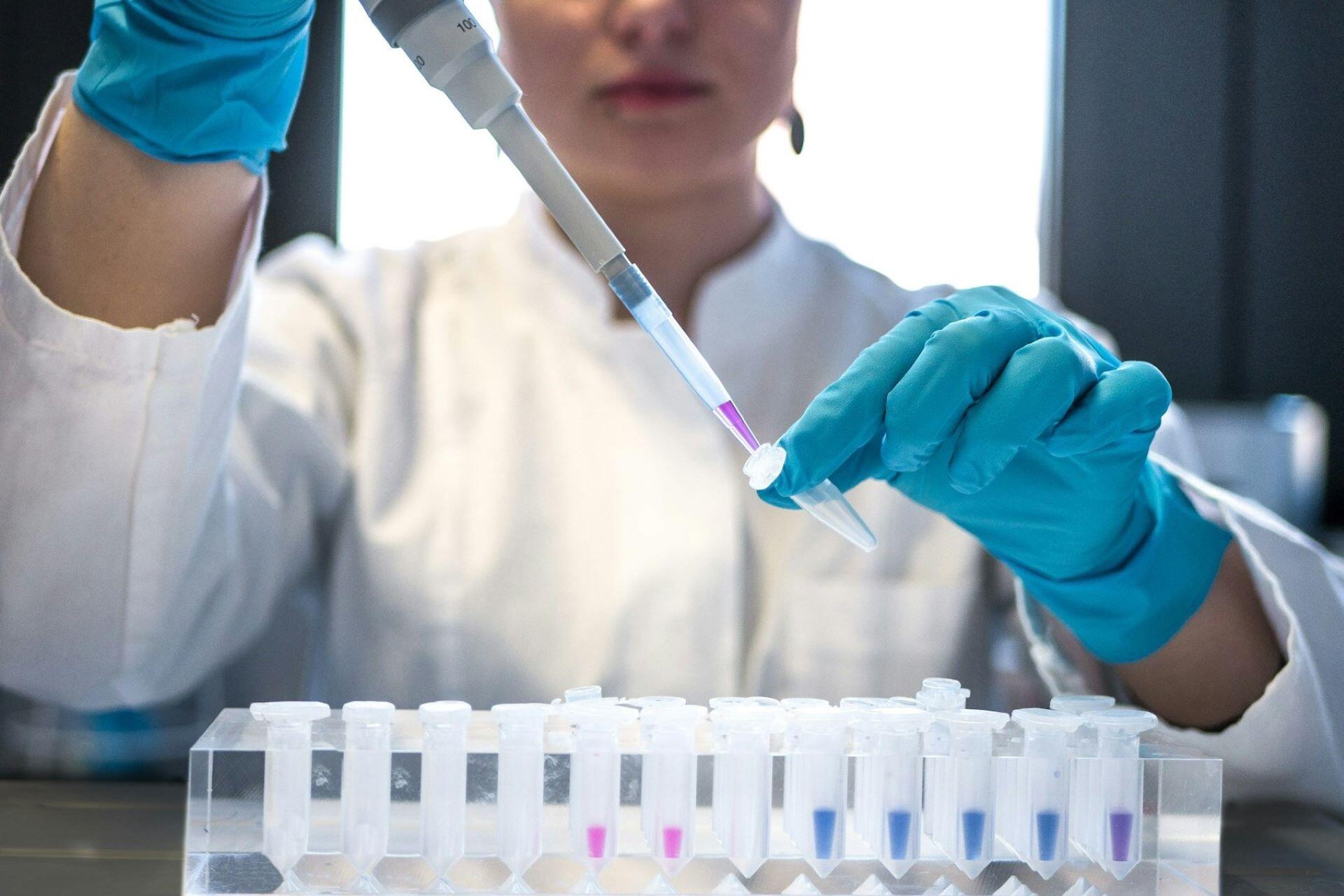 Scientist using a pipette to transfer liquid into a sample tube