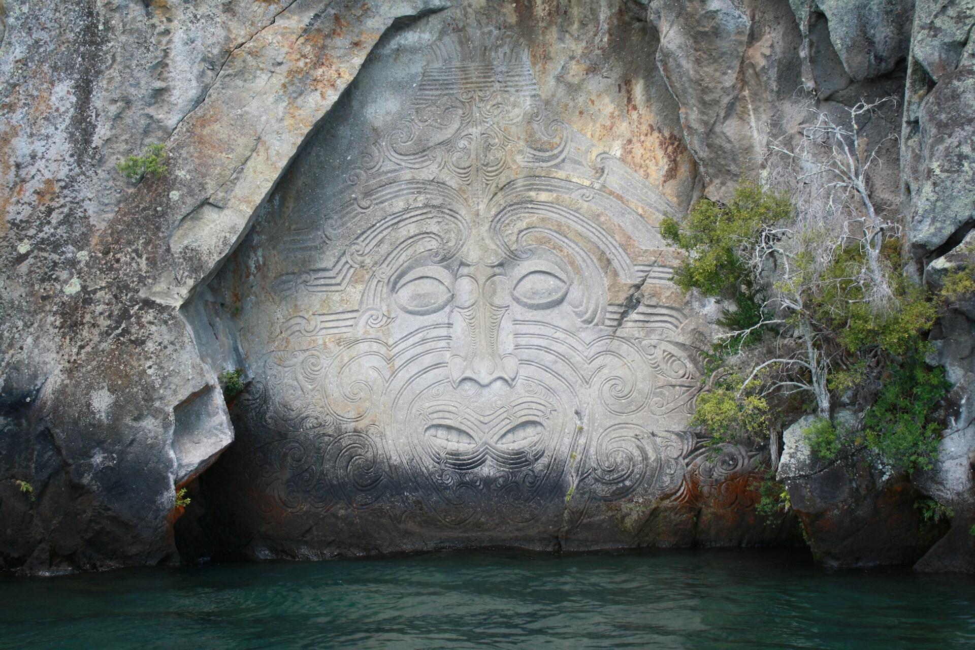 A Maori stone carving by a body of water. 