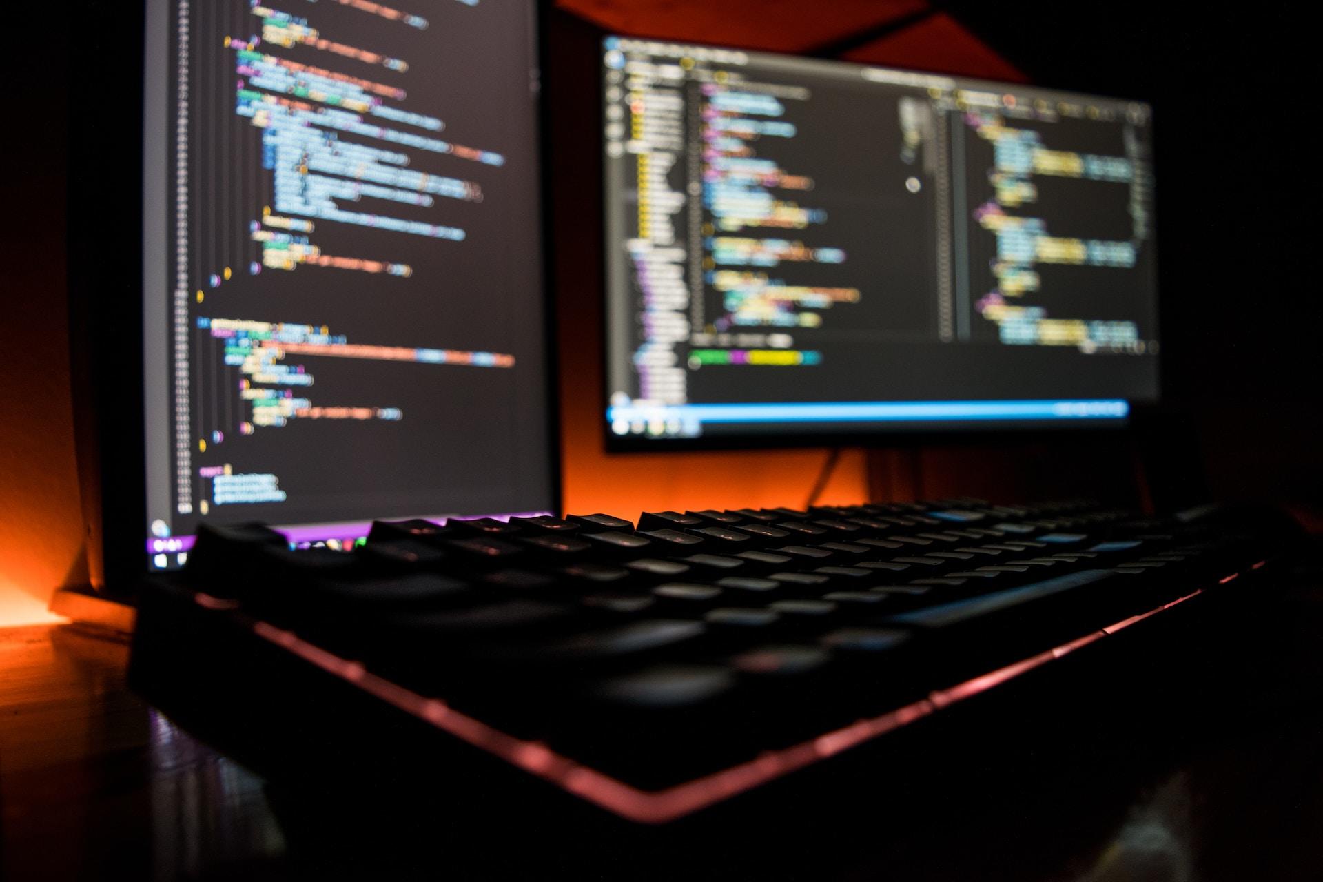 A view of a computer with two monitors with code on them.