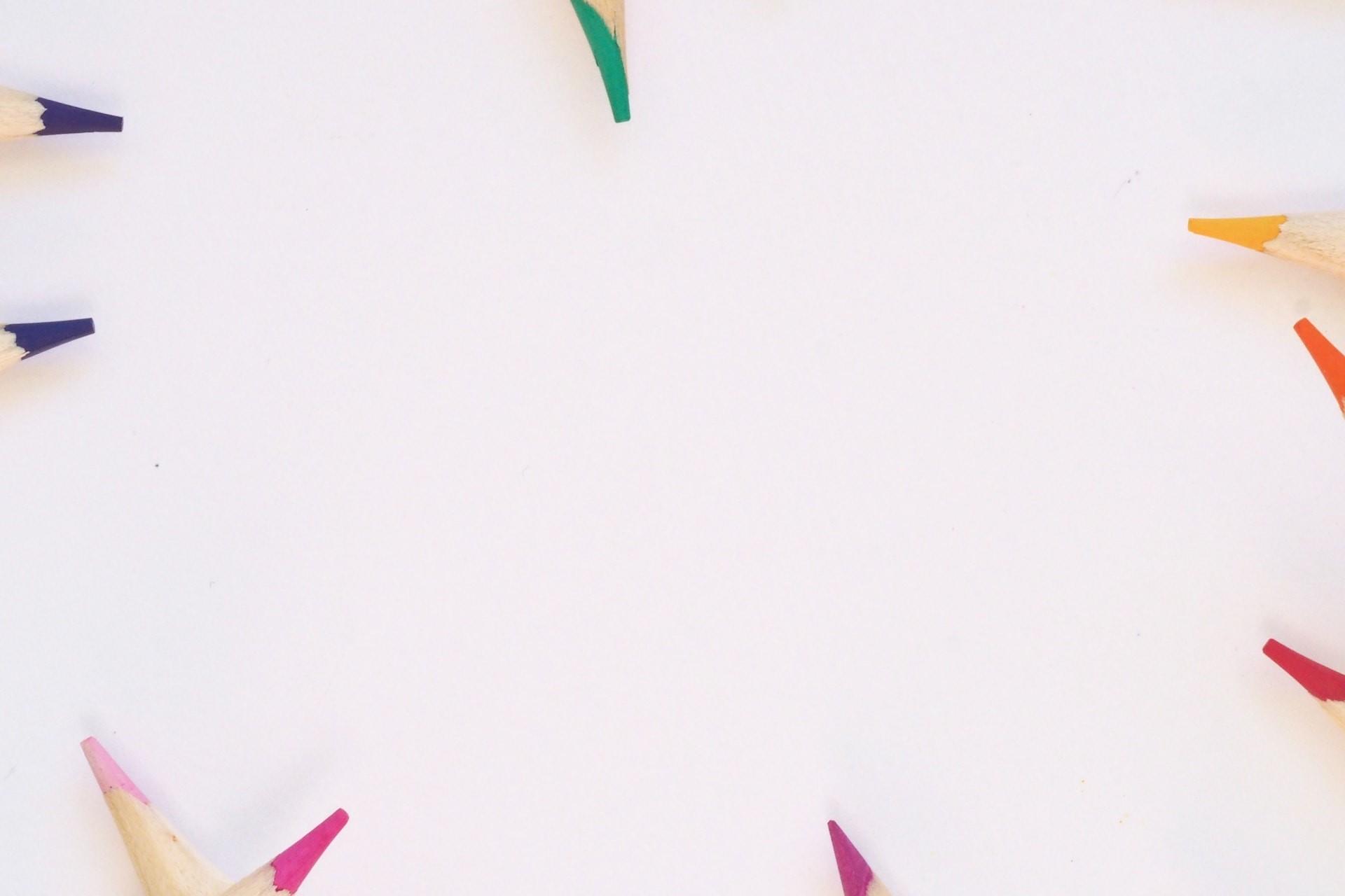 Coloured pencils around a blank piece of paper.