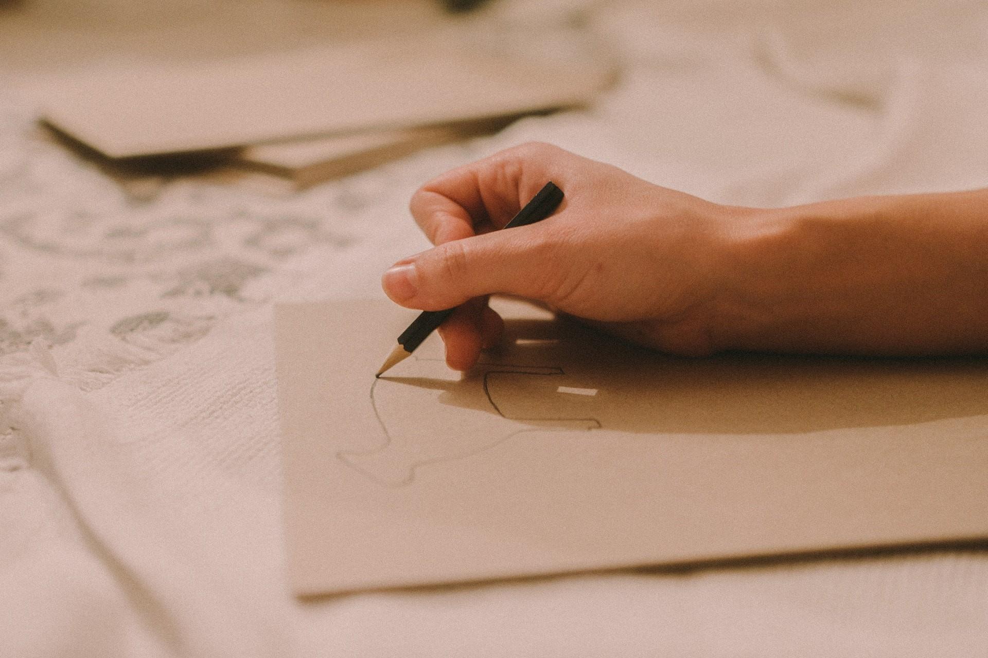 A hand sketching with a pencil.