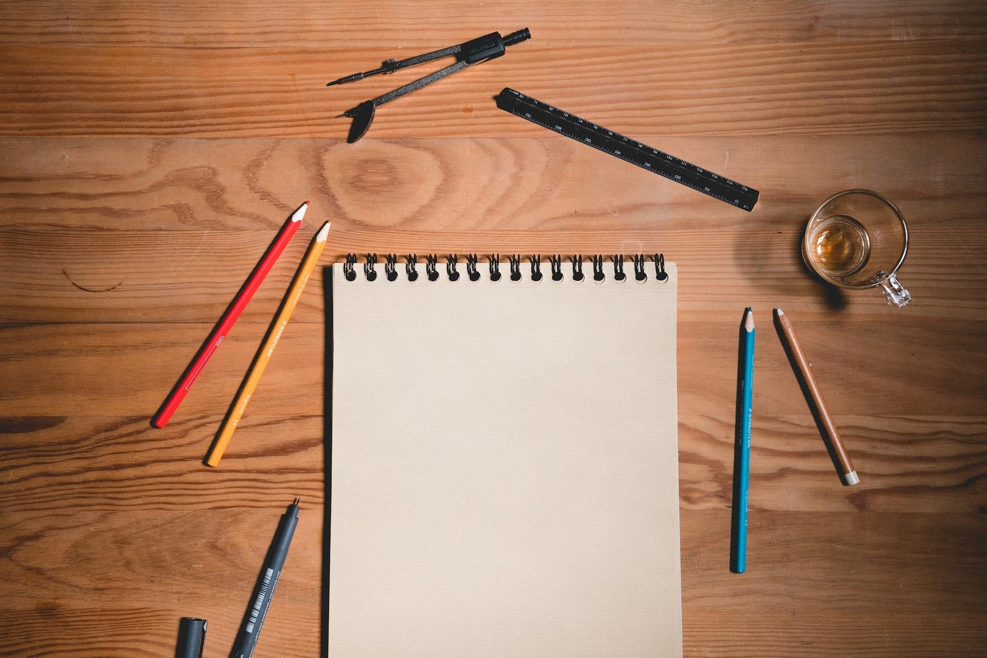 A notebook or sketchpad surrounded by drawing supplies.