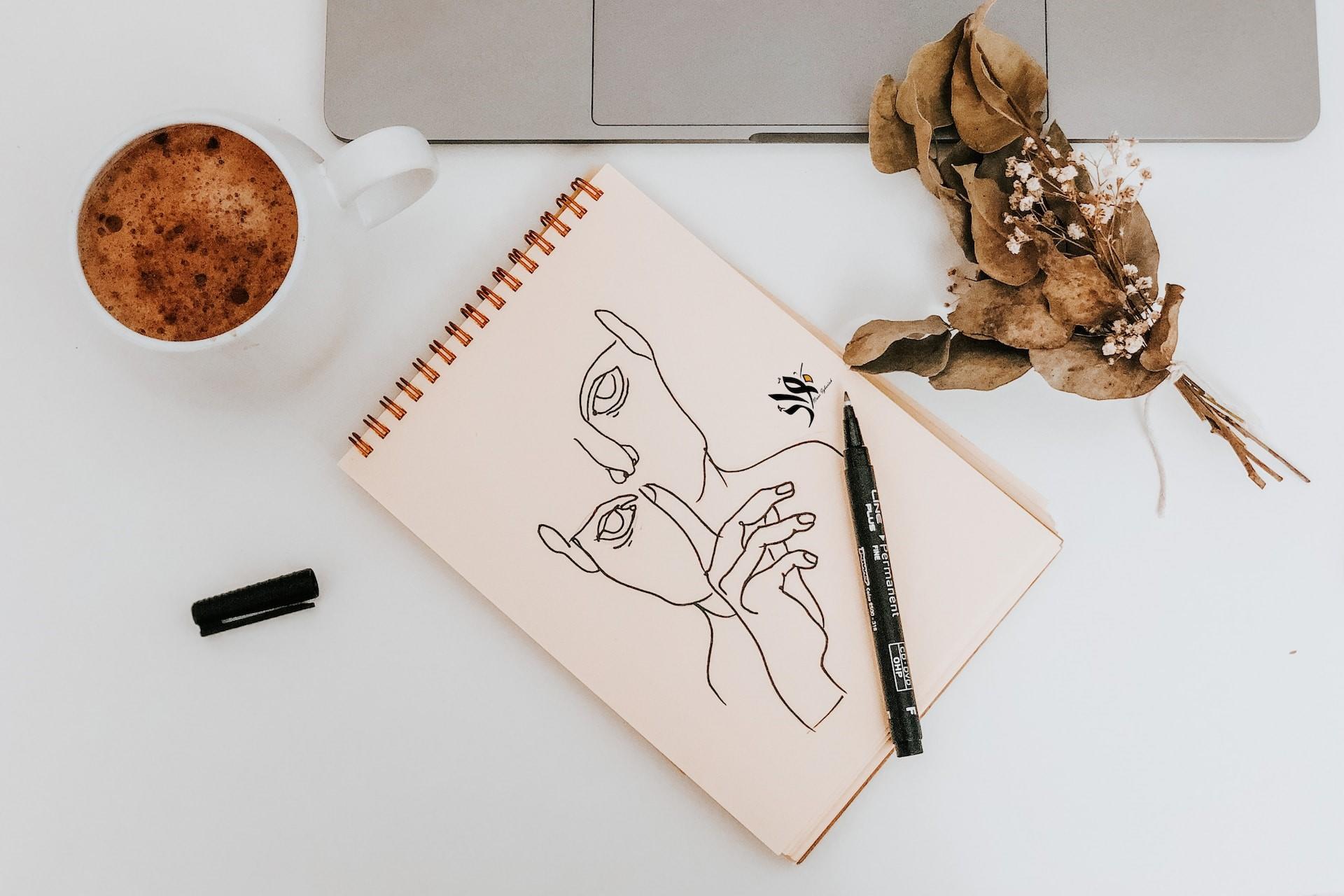 A drawing on a sketchpad next to a laptop.