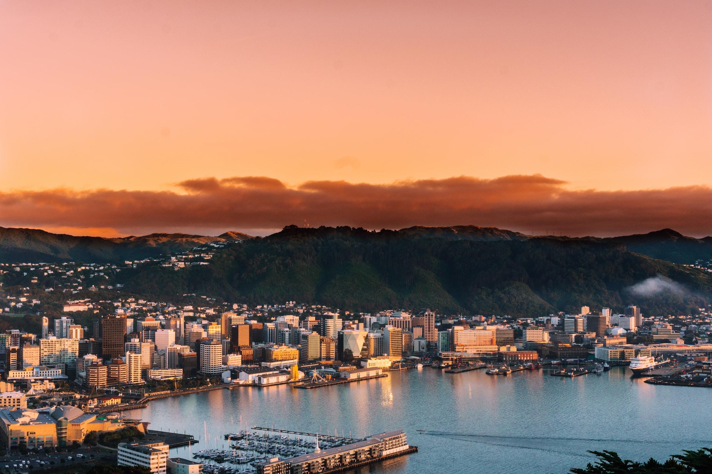 A landscape photo of Wellington city at sunrise with mountains in the background.