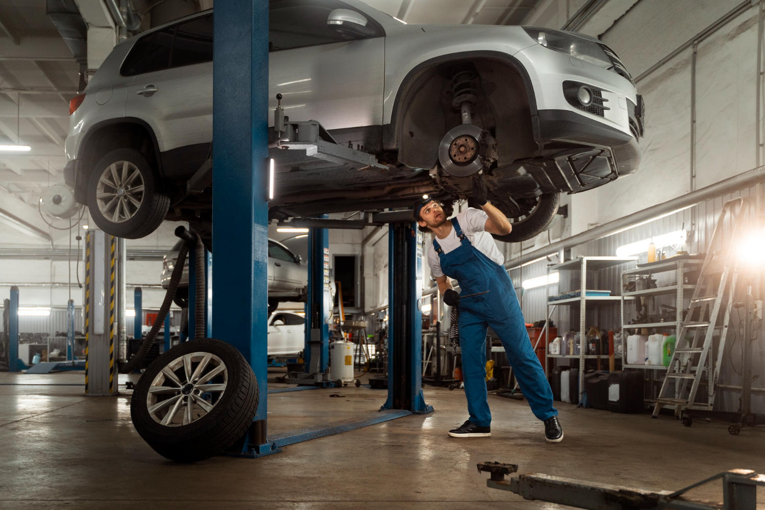 An auto mechanic looking at a lifted car