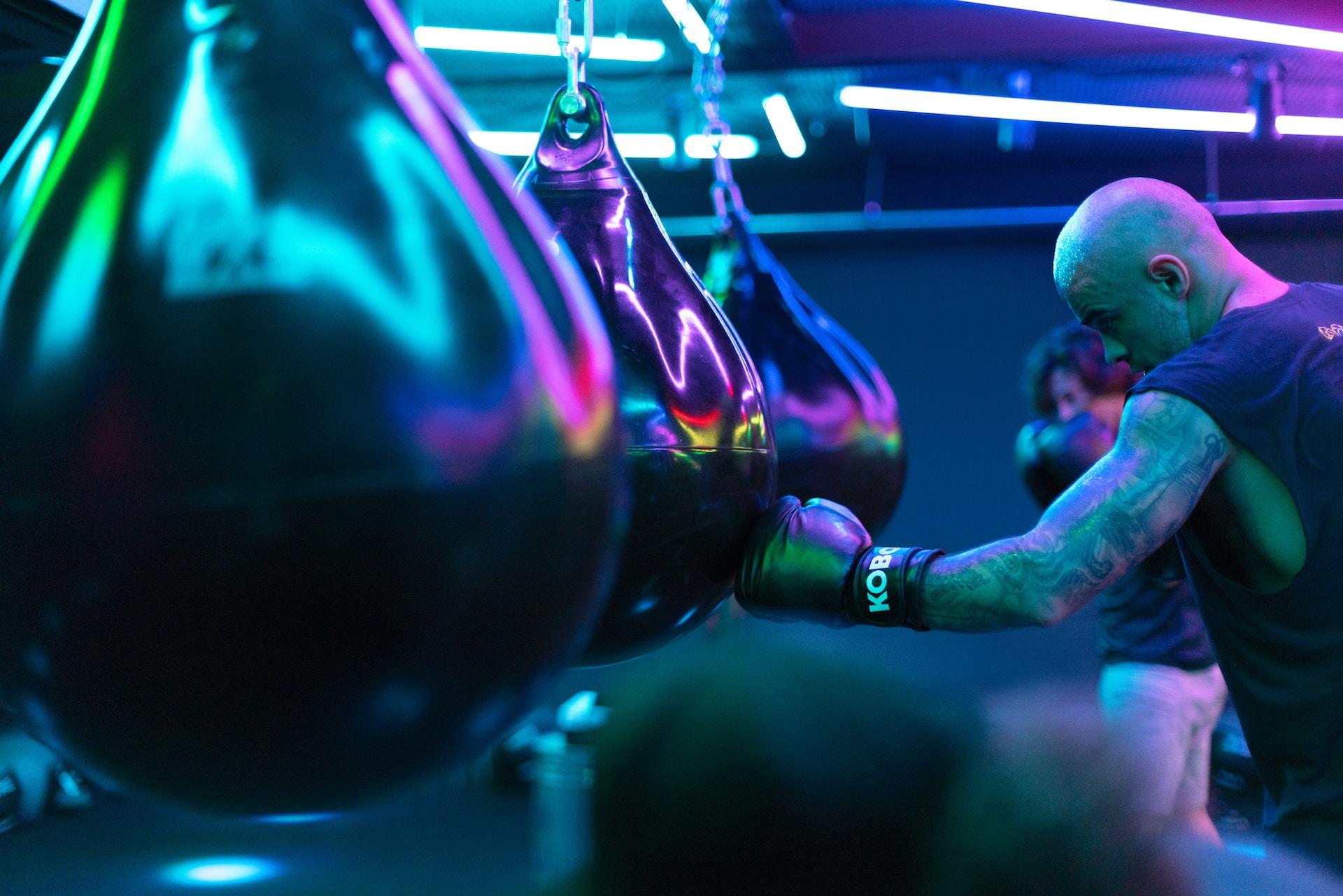 People using punching bags in a boxing gym.