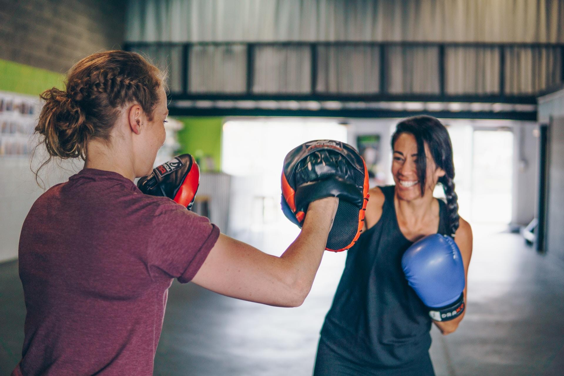 Two people practising boxing technique with pads.