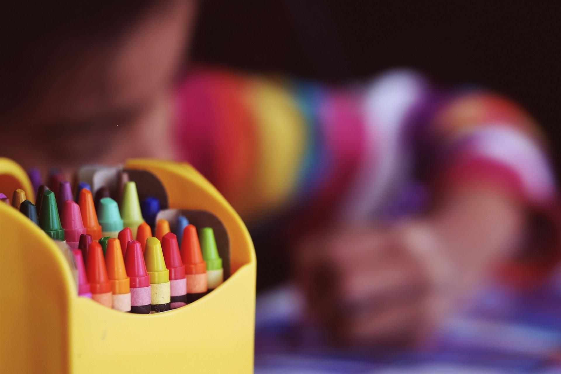 A child drawing next to some crayons.