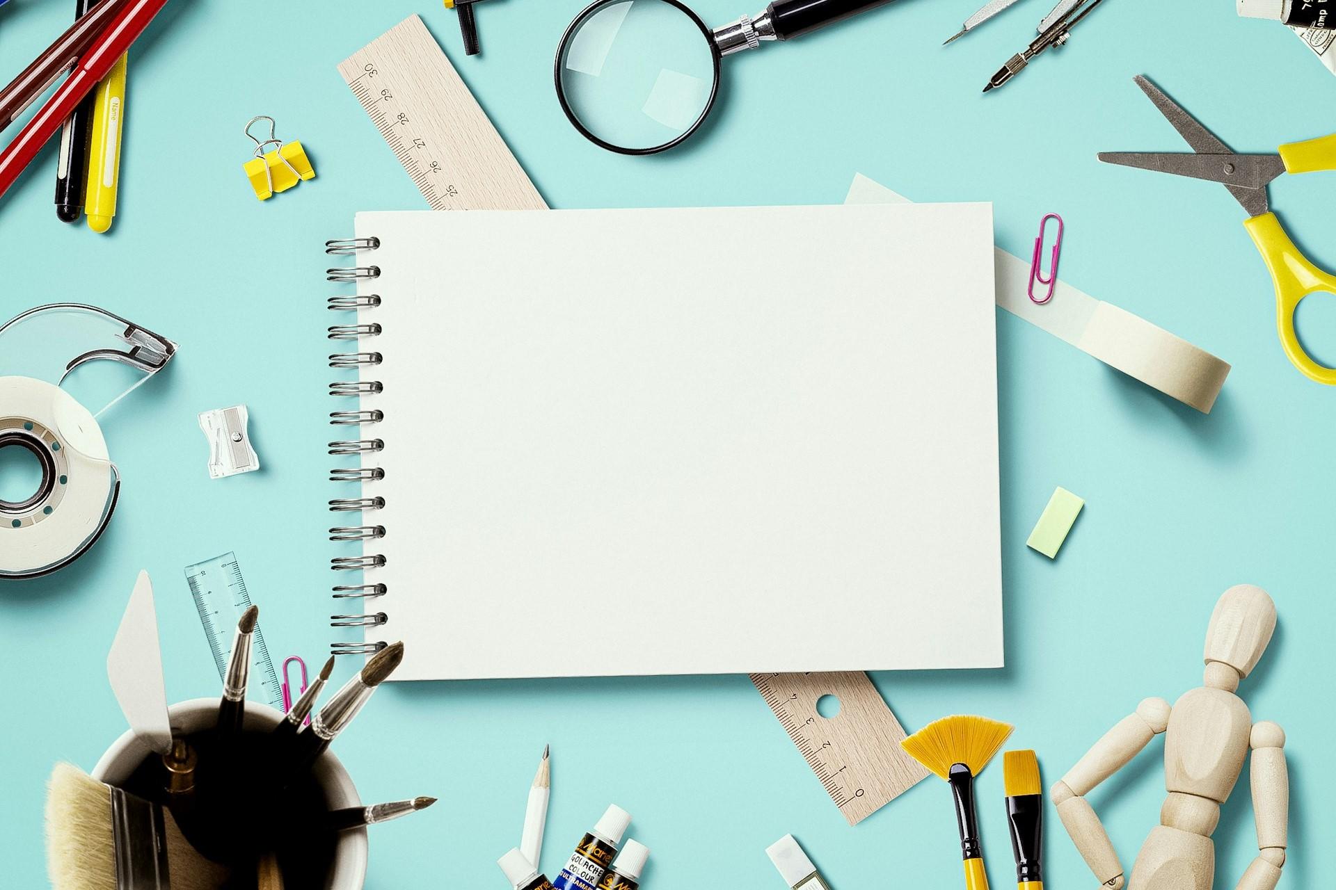 A sketchpad surrounded by art supplies.