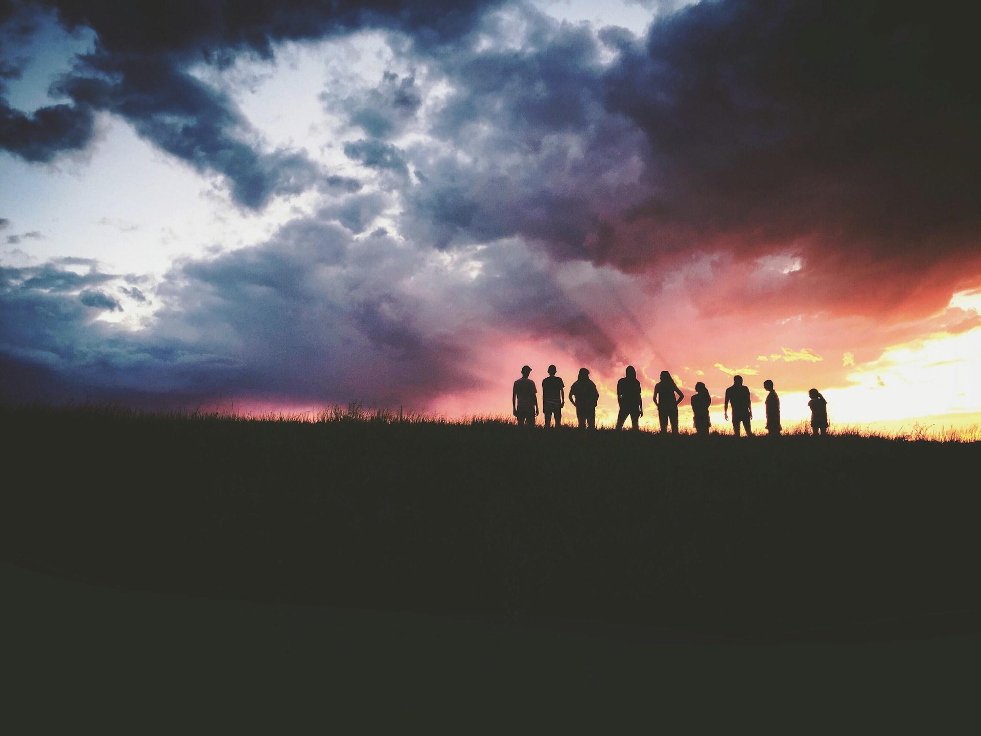 A view of people outdoors at sunset.