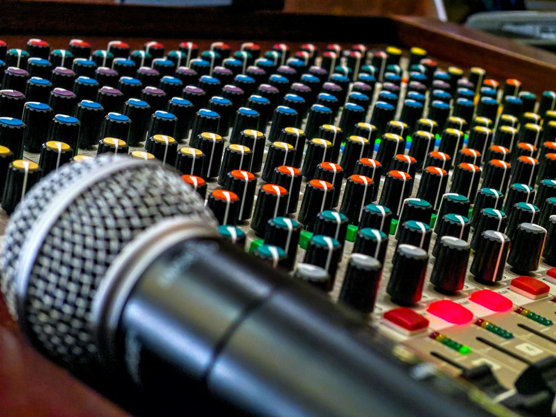 A microphone by a mixing desk.