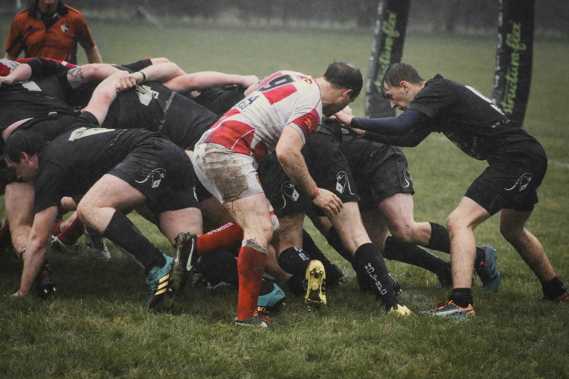 Several rugby players in a scrum in the rain.