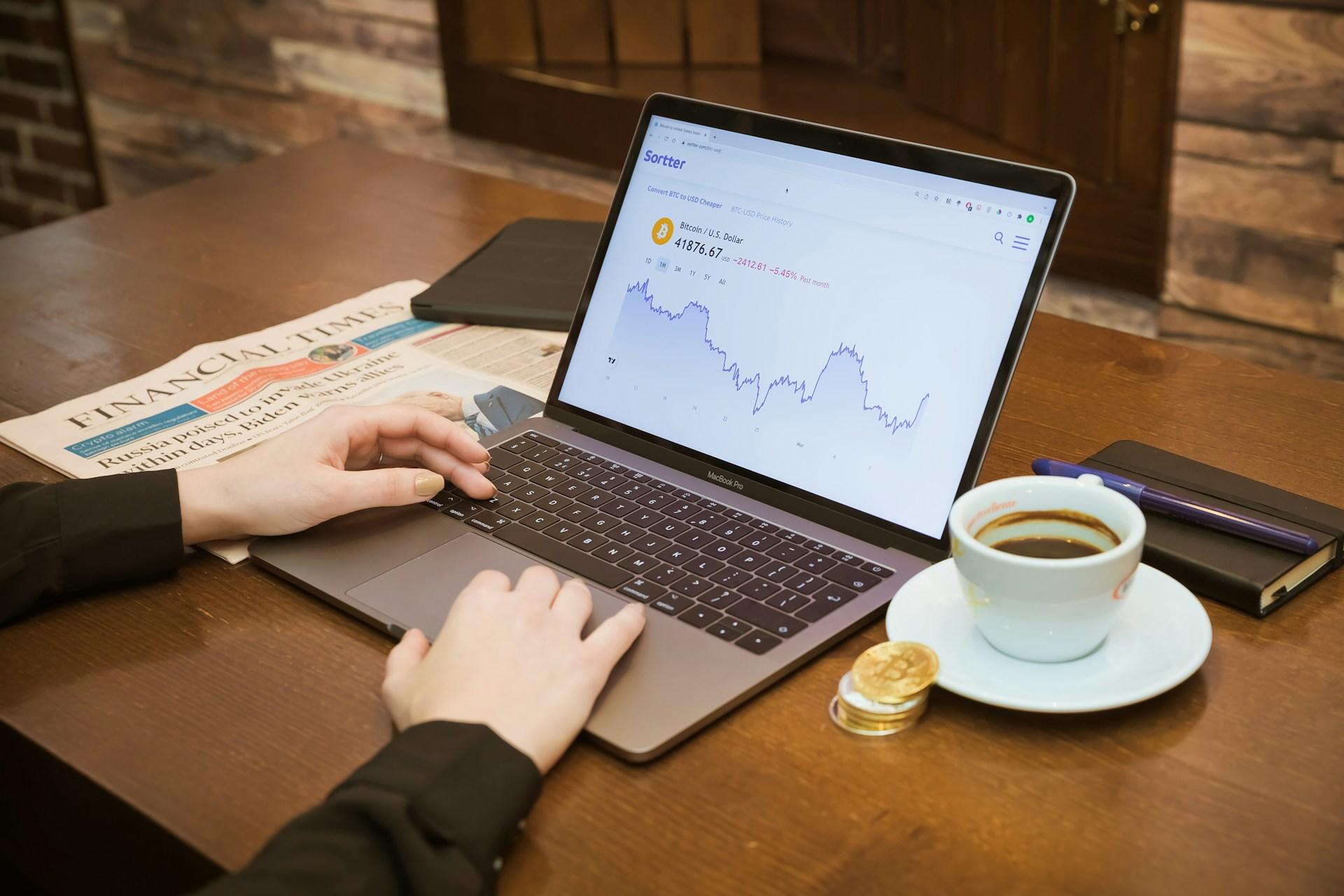 A person using a laptop to look at the value of Bitcoin.