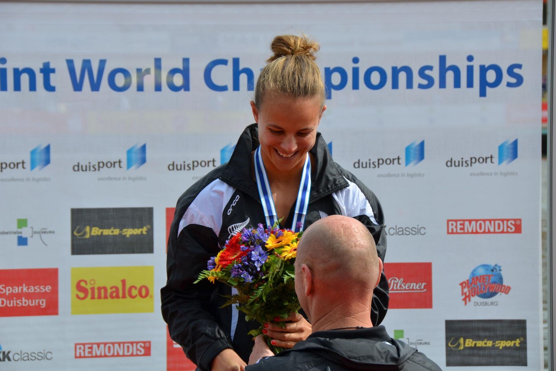 Lisa Carrington receiving a medal and holding flowers at a sporting event