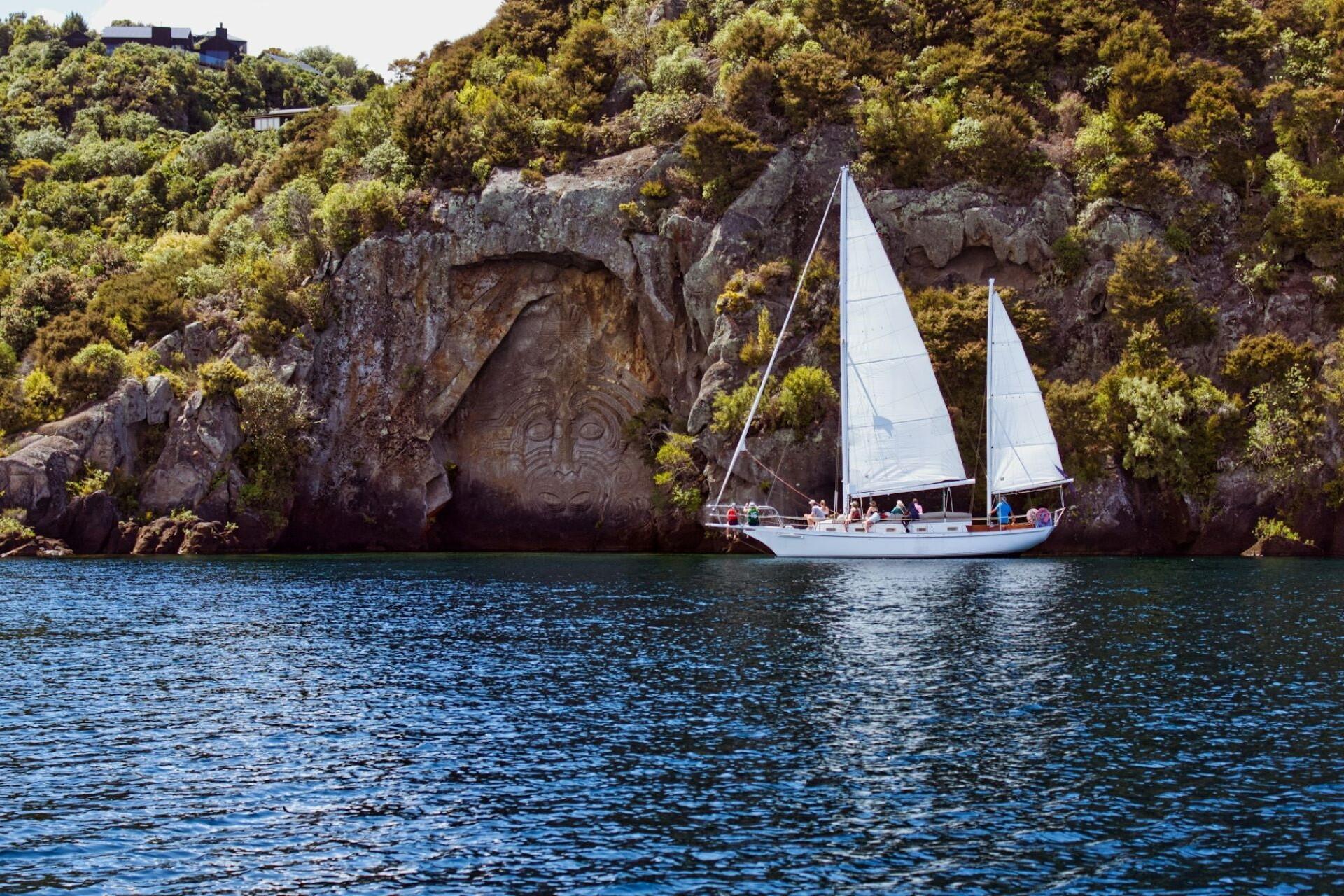 A boat sailing by a Maori stone carving.