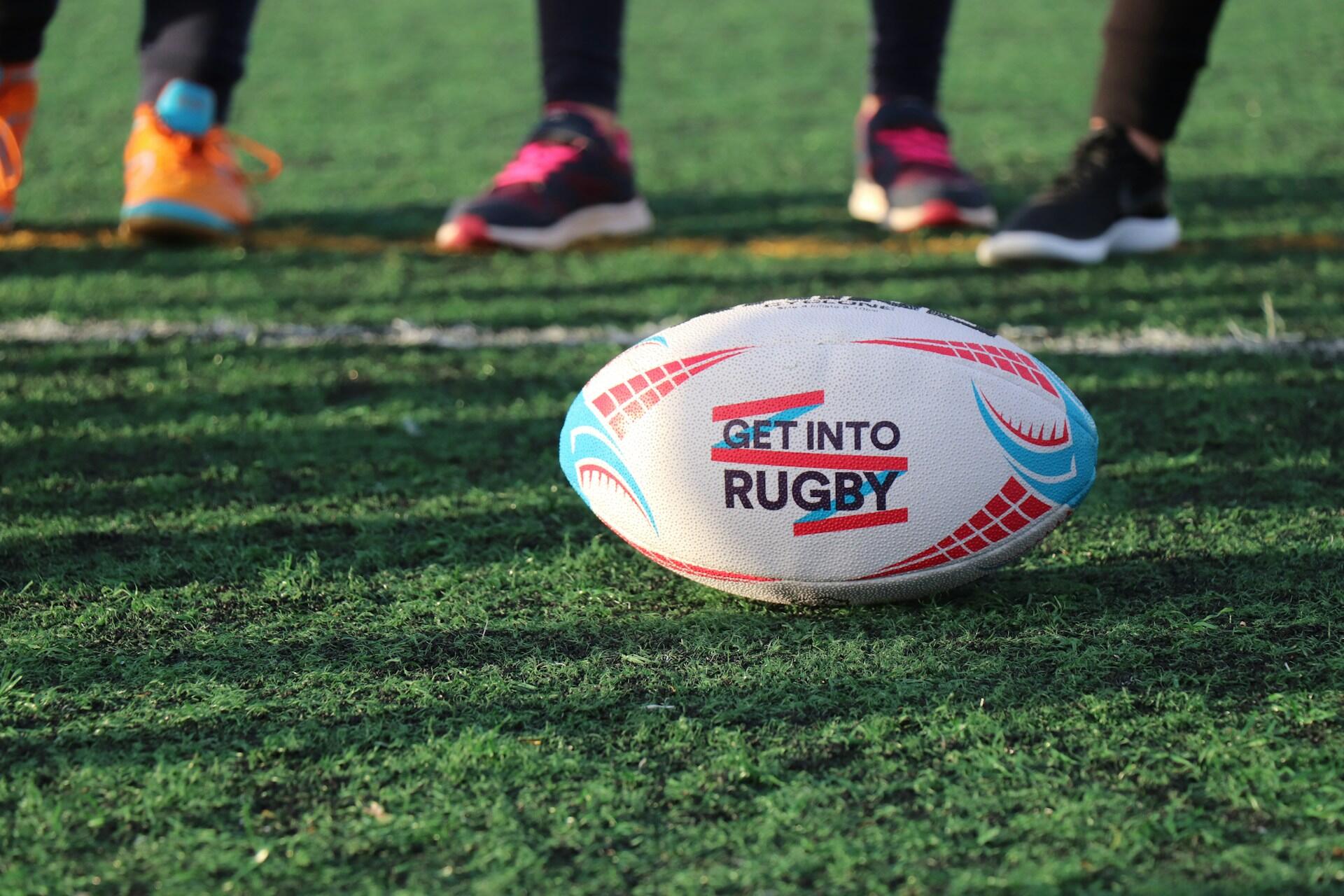 Rugby ball on a training pitch with players standing in the background