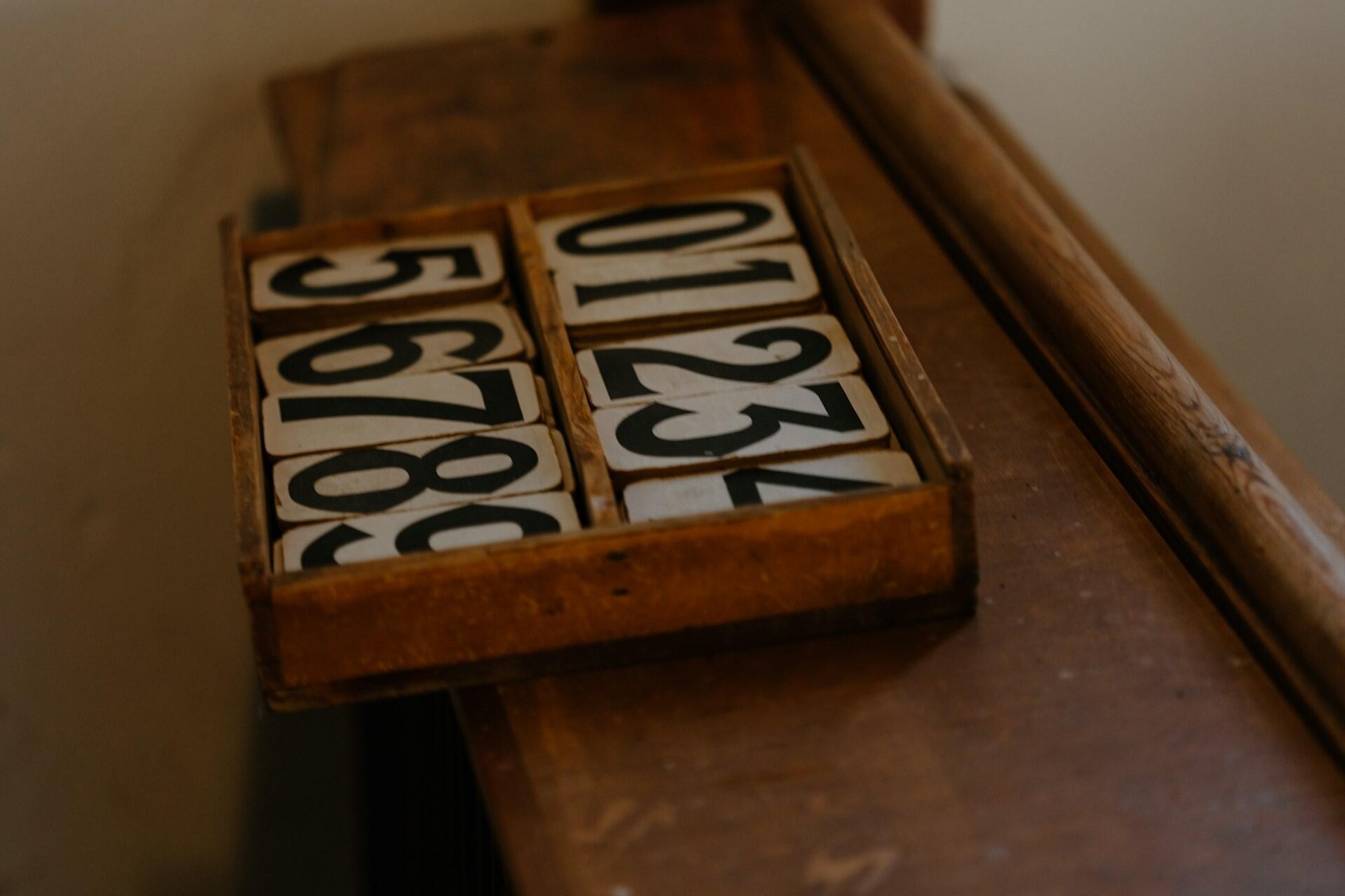 Wooden tray holding printed number blocks arranged in rows.