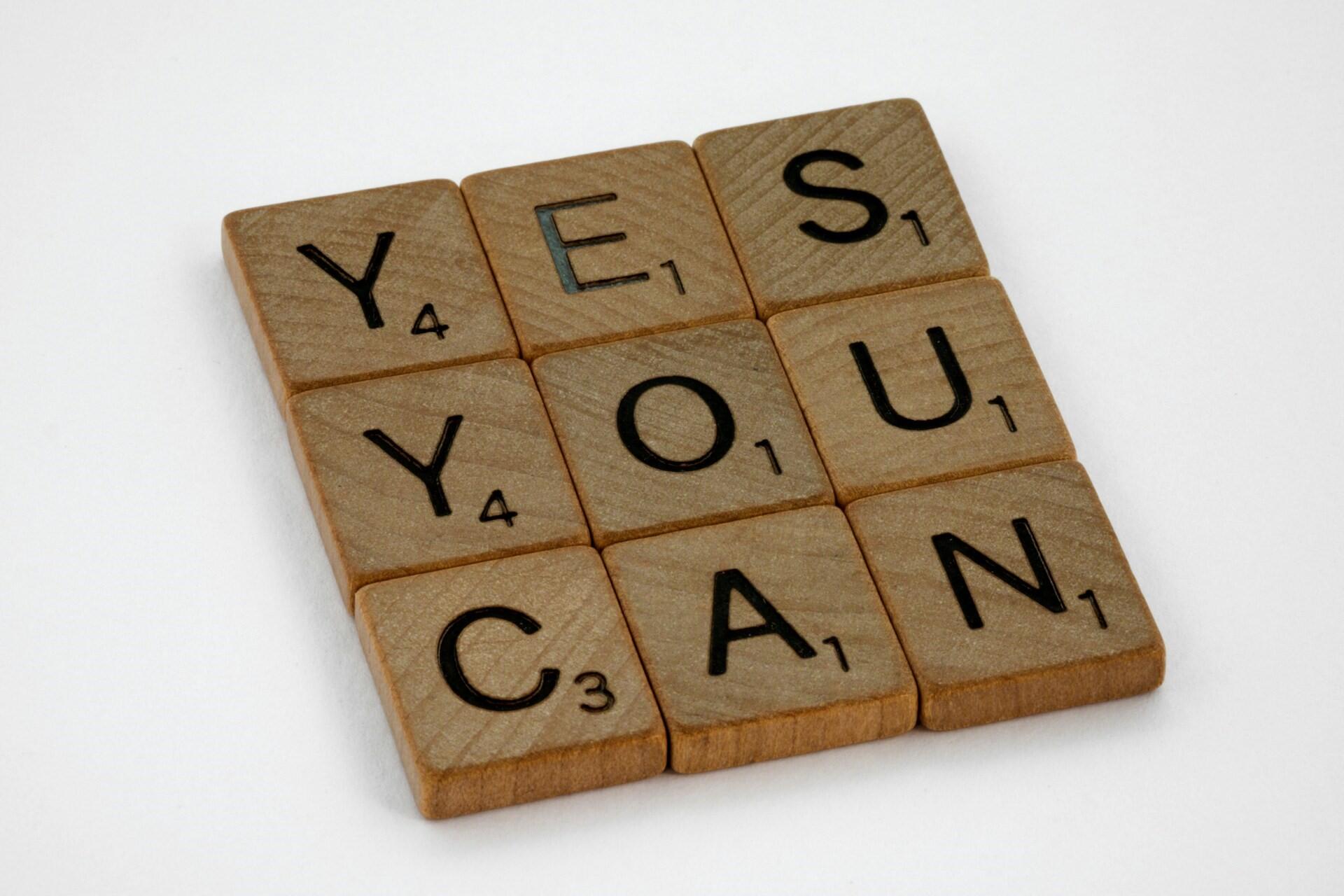 Wooden letter tiles spelling the phrase “YES YOU CAN”