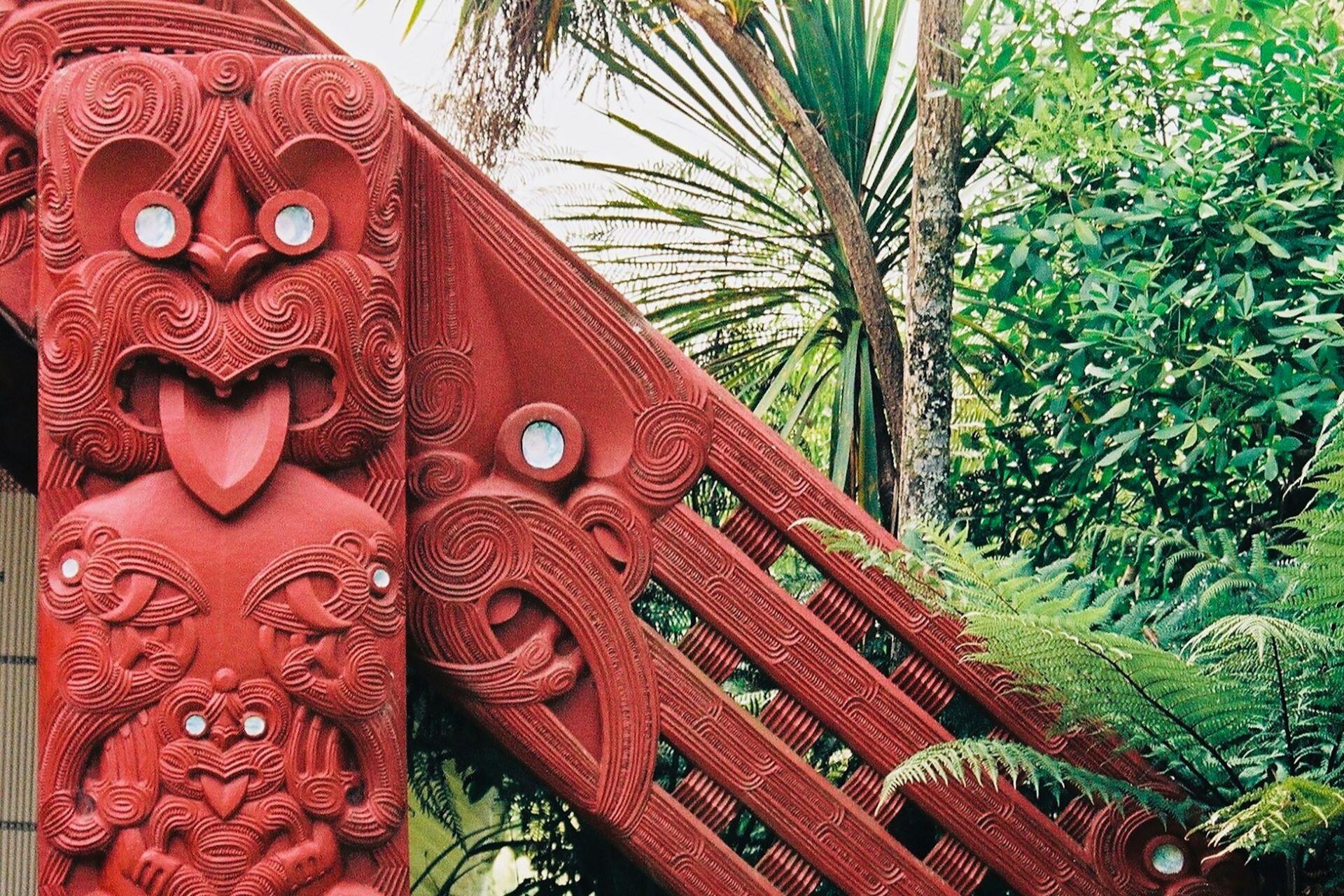 Traditional Māori carving on a red wooden structure in New Zealand