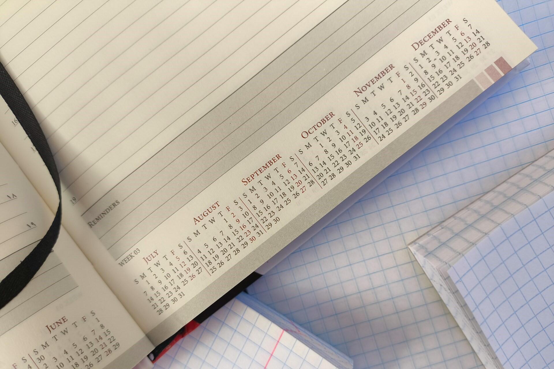 Open planner showing calendar dates beside notebooks