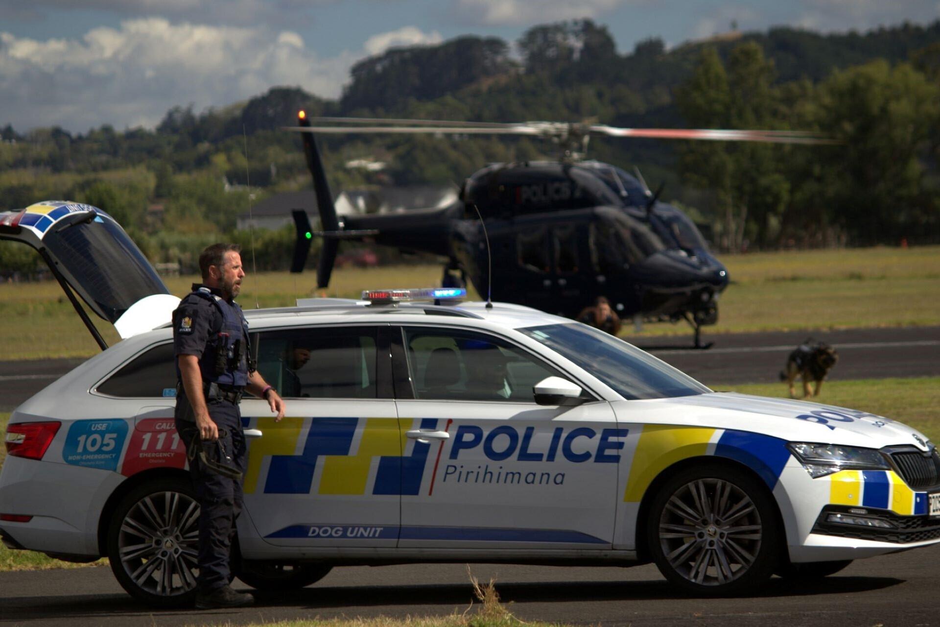 A New Zealand policeman, car, and helicopter.