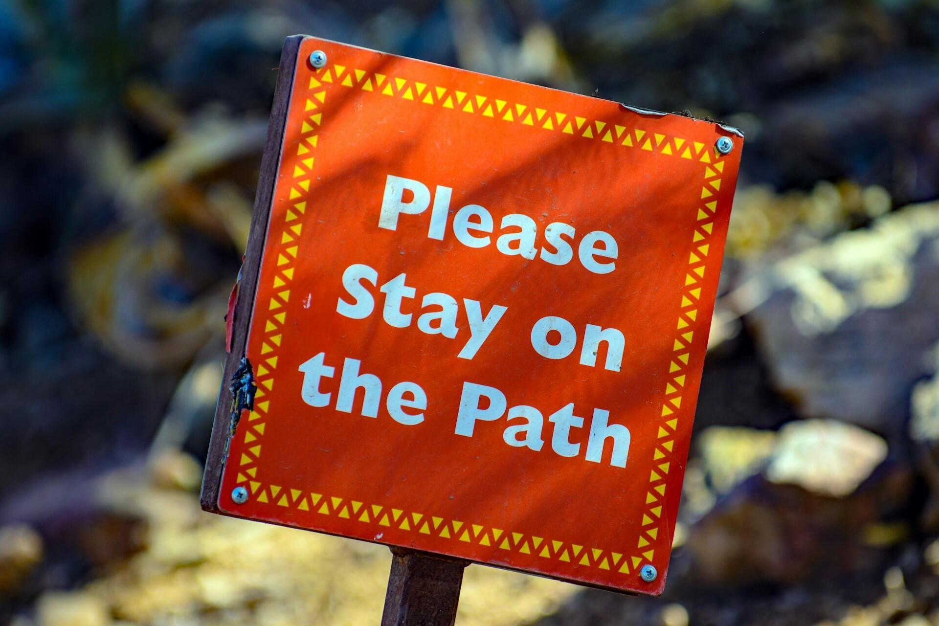 A sign that says "Please Stay on the Path"