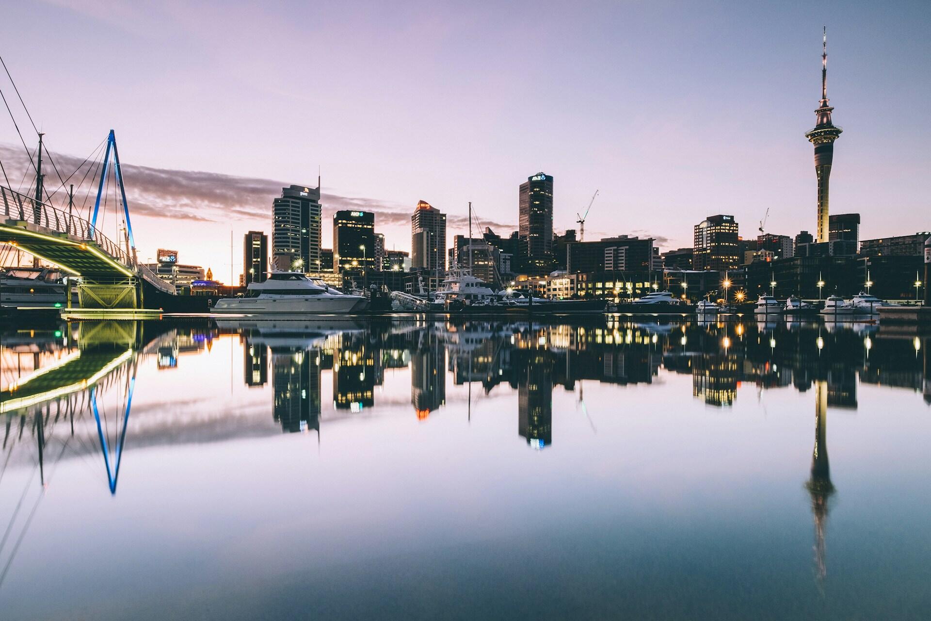 Auckland skyline and Sky Tower reflected in harbour water at dusk