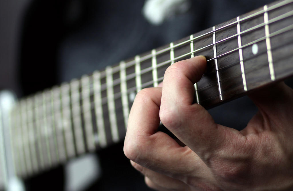 A guitarist plays the neck of the guitar.