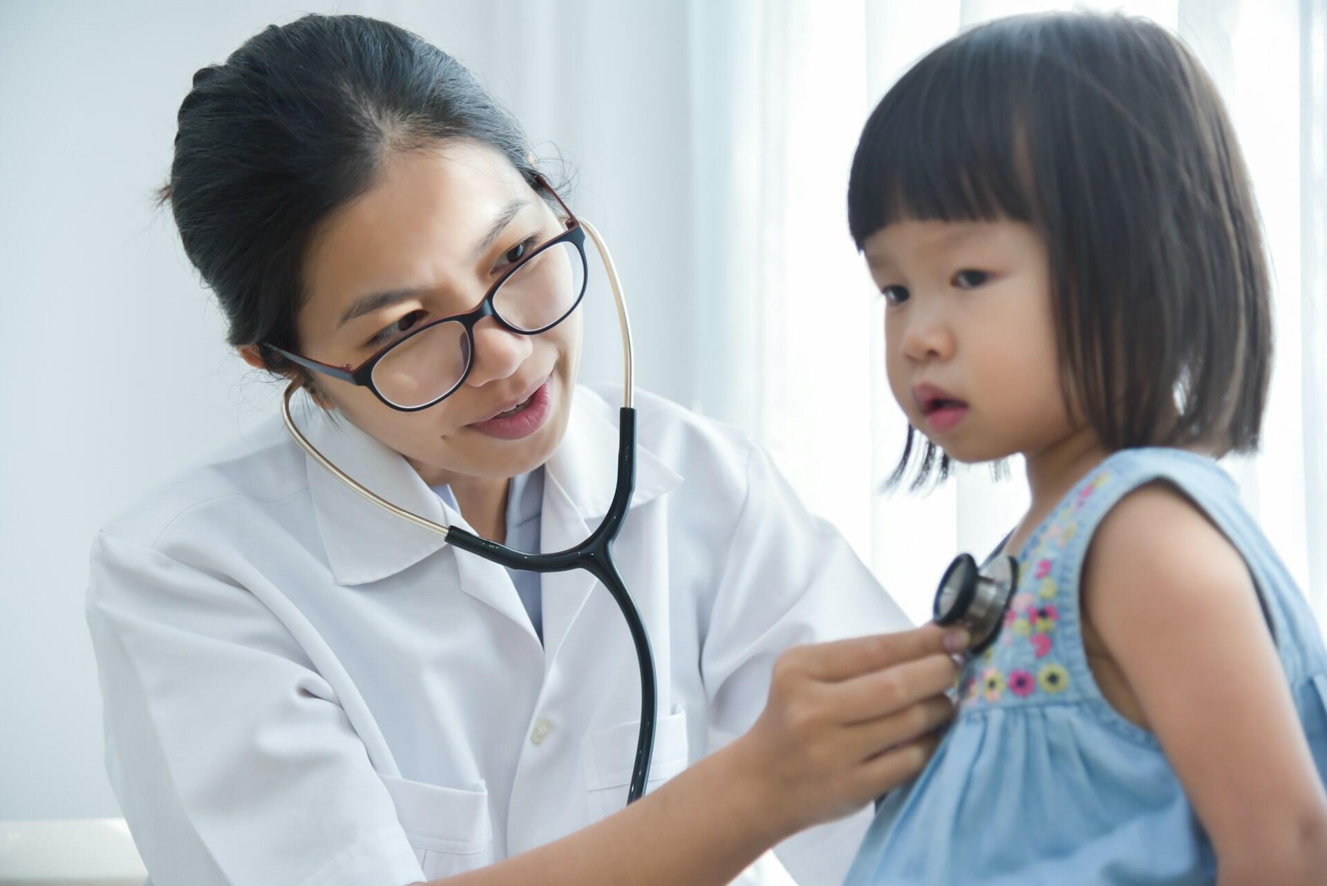 female nurse listening to heartbeat of a young child.
