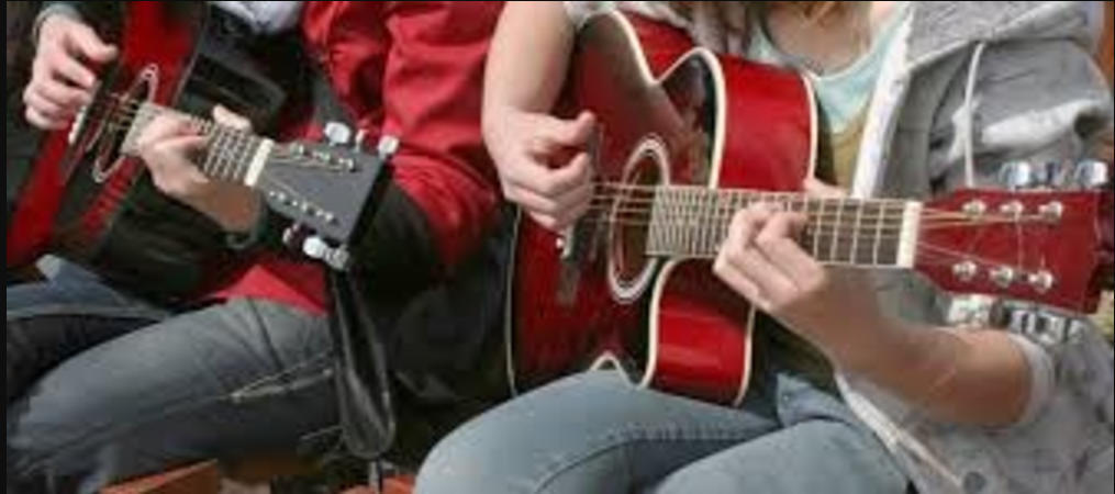 Two children sat playing the guitar.